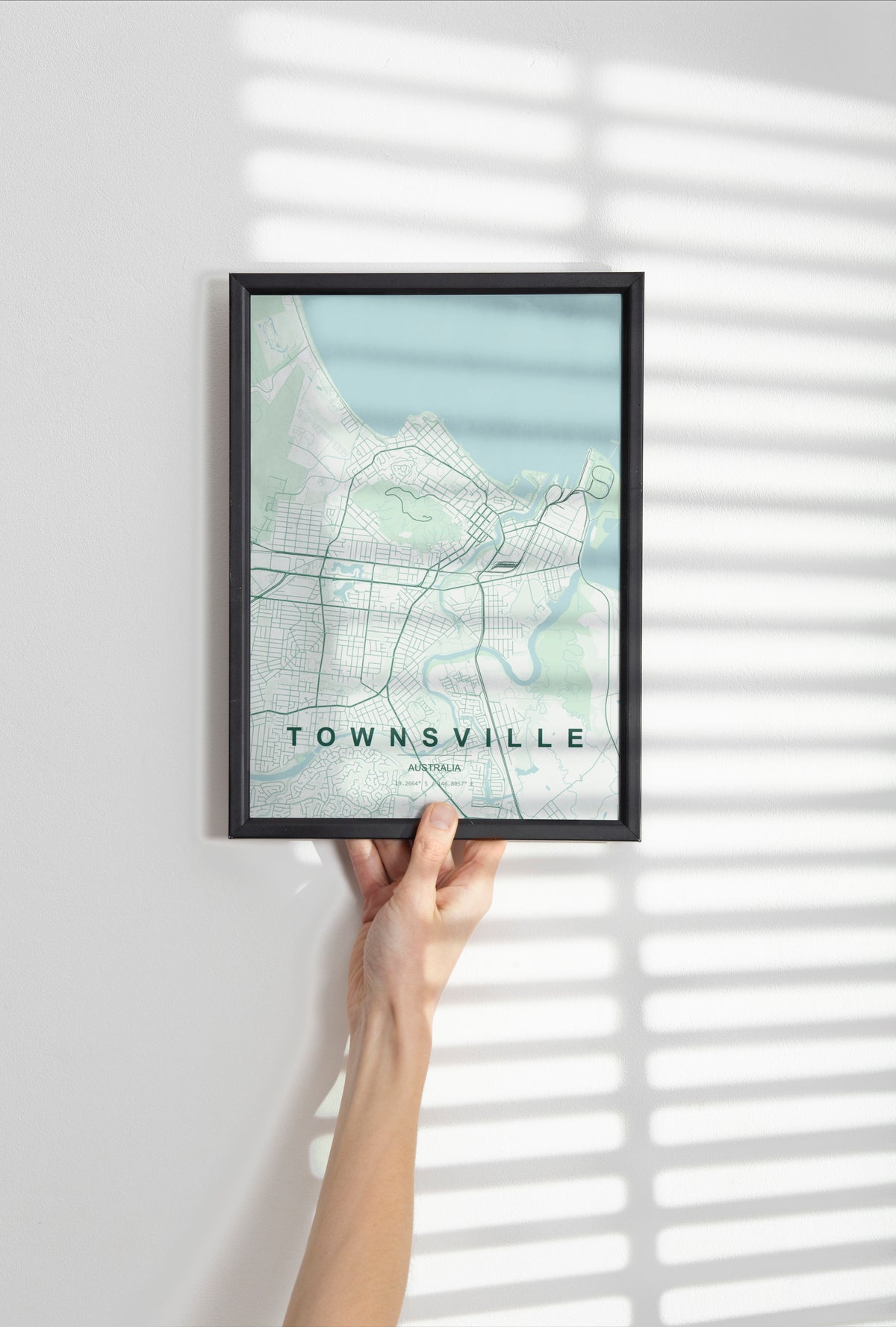 Townsville, Queensland, Australia map print in the Forest theme in a black frame held against a pale wall