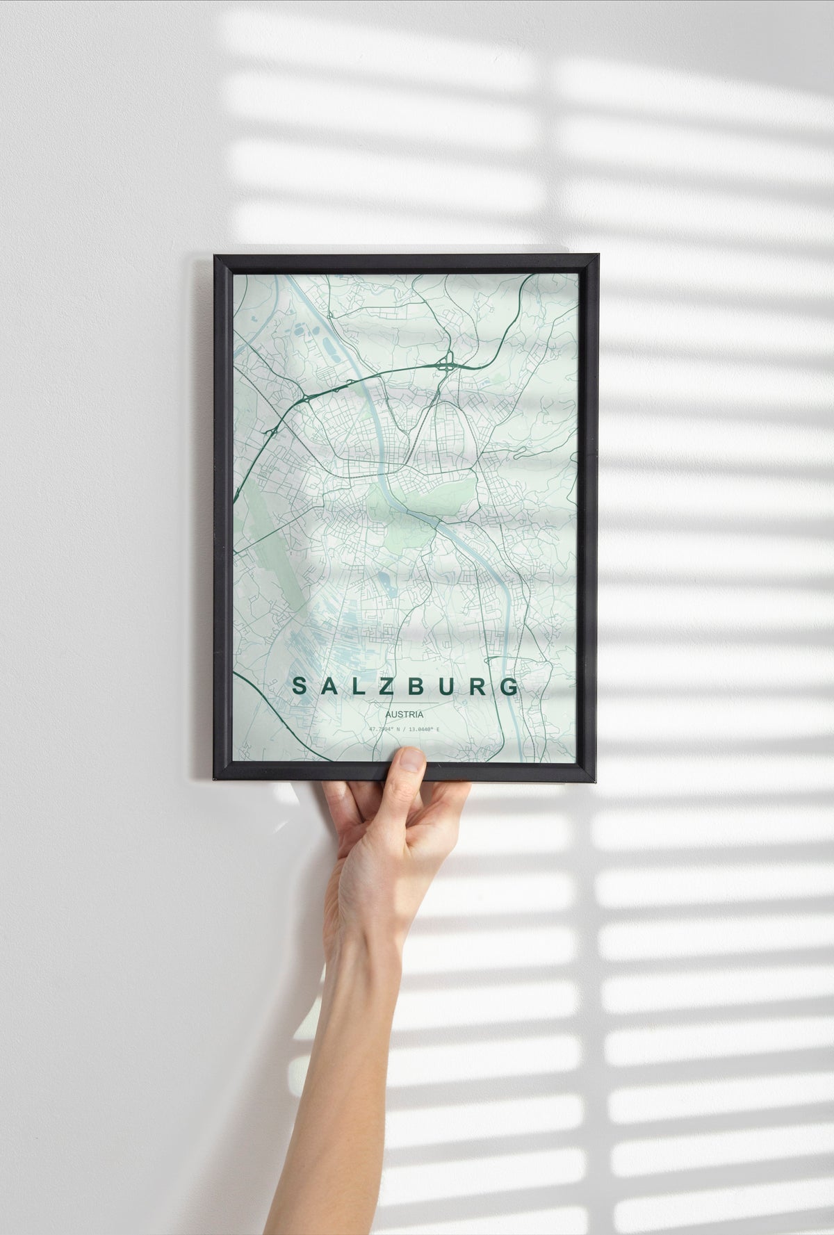 Salzburg map print in the Forest theme in a black frame held against a pale wall