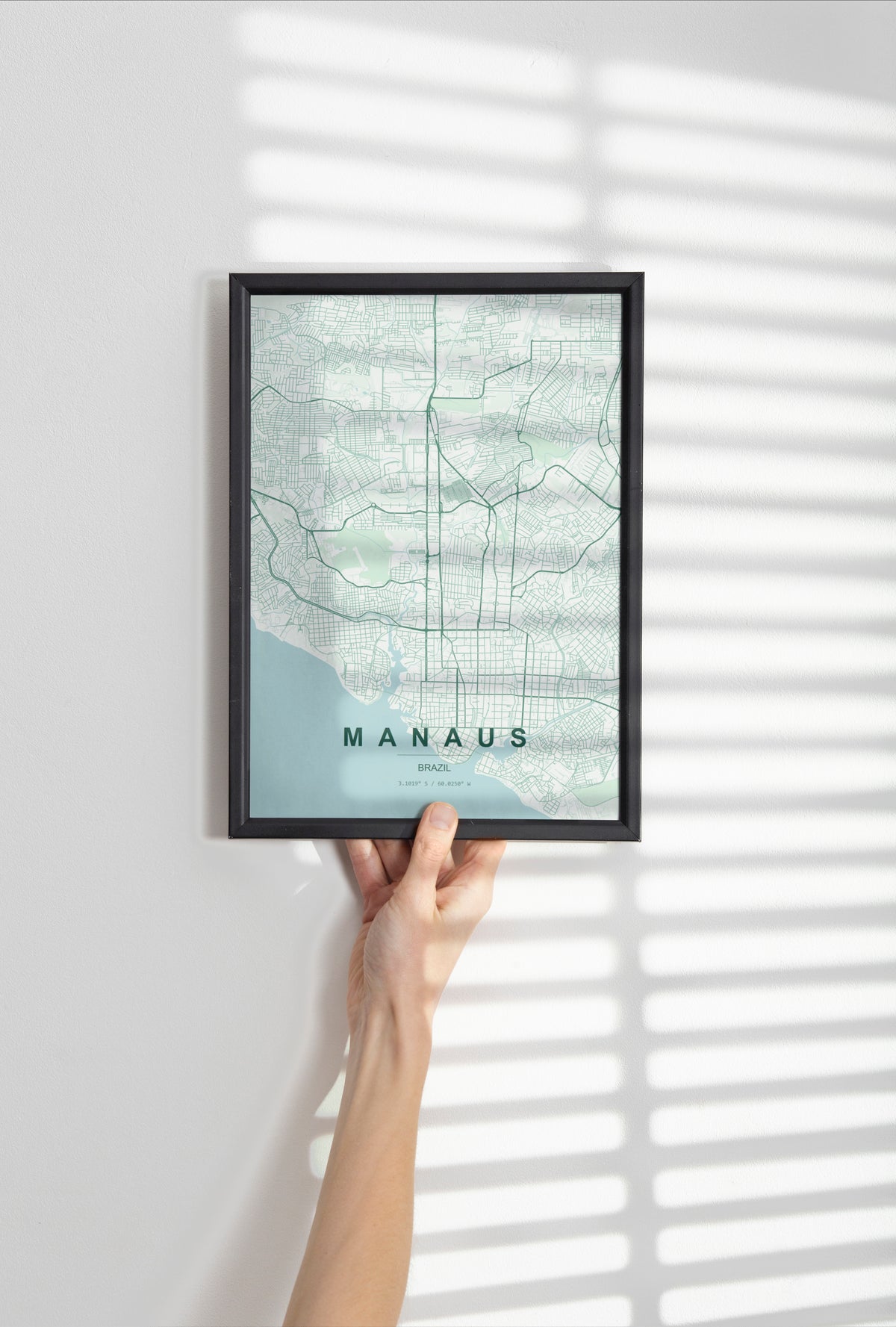 Manaus, Brazil map print in the Forest theme in a black frame held against a pale wall