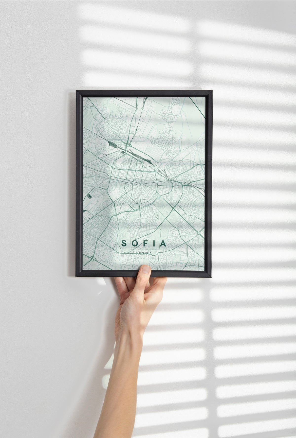 Sofia map print in the Forest theme in a black frame held against a pale wall
