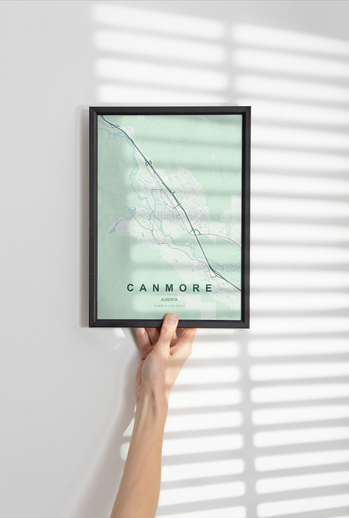 Canmore, Alberta, Canada map print in the Forest theme in a black frame held against a pale wall