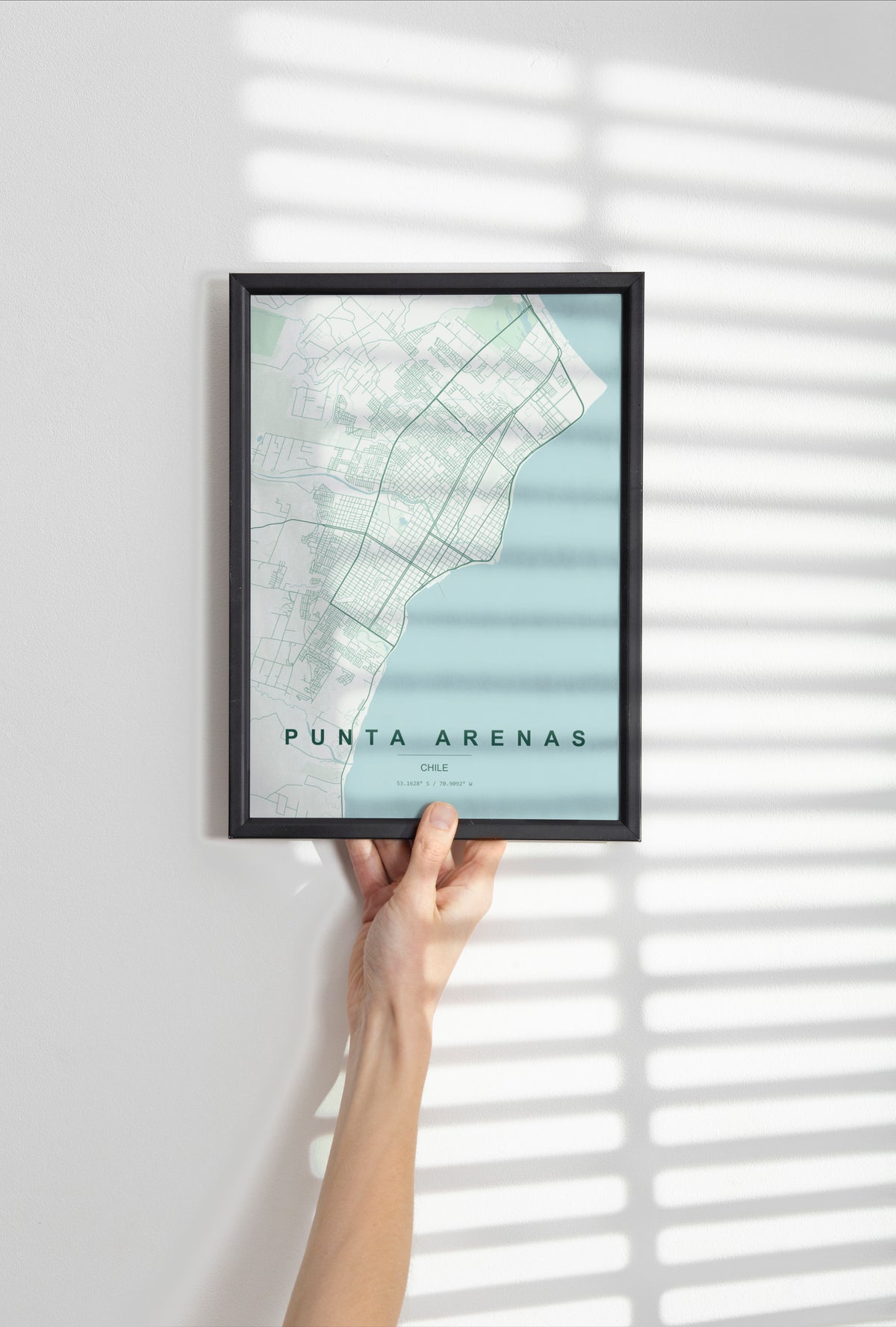 Punta Arenas, Chile map print in the Forest theme in a black frame held against a pale wall