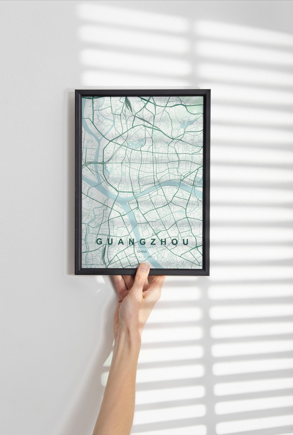 Guangzhou, China map print in the Forest theme in a black frame held against a pale wall