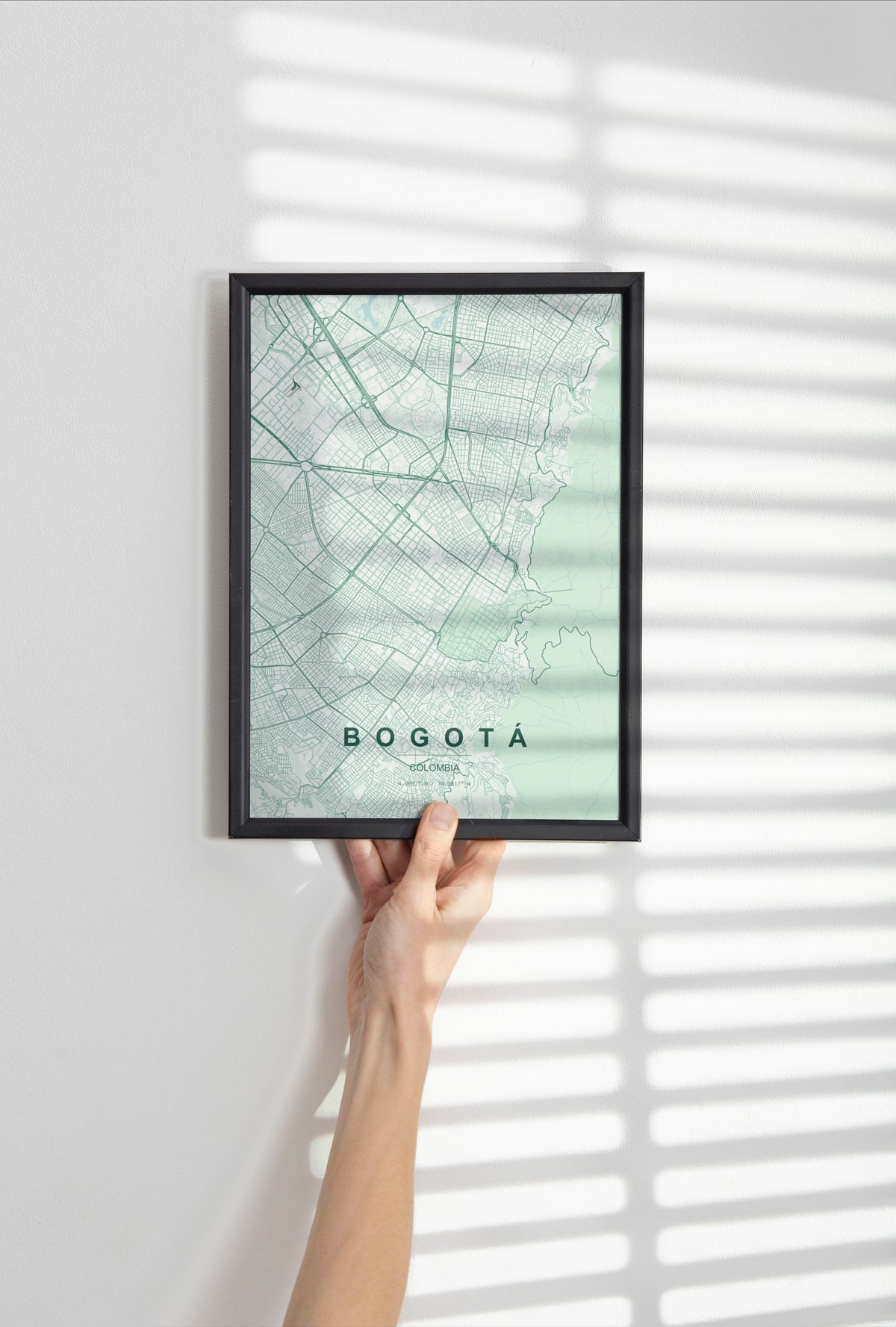 Bogotá, Colombia map print in the Forest theme in a black frame held against a pale wall