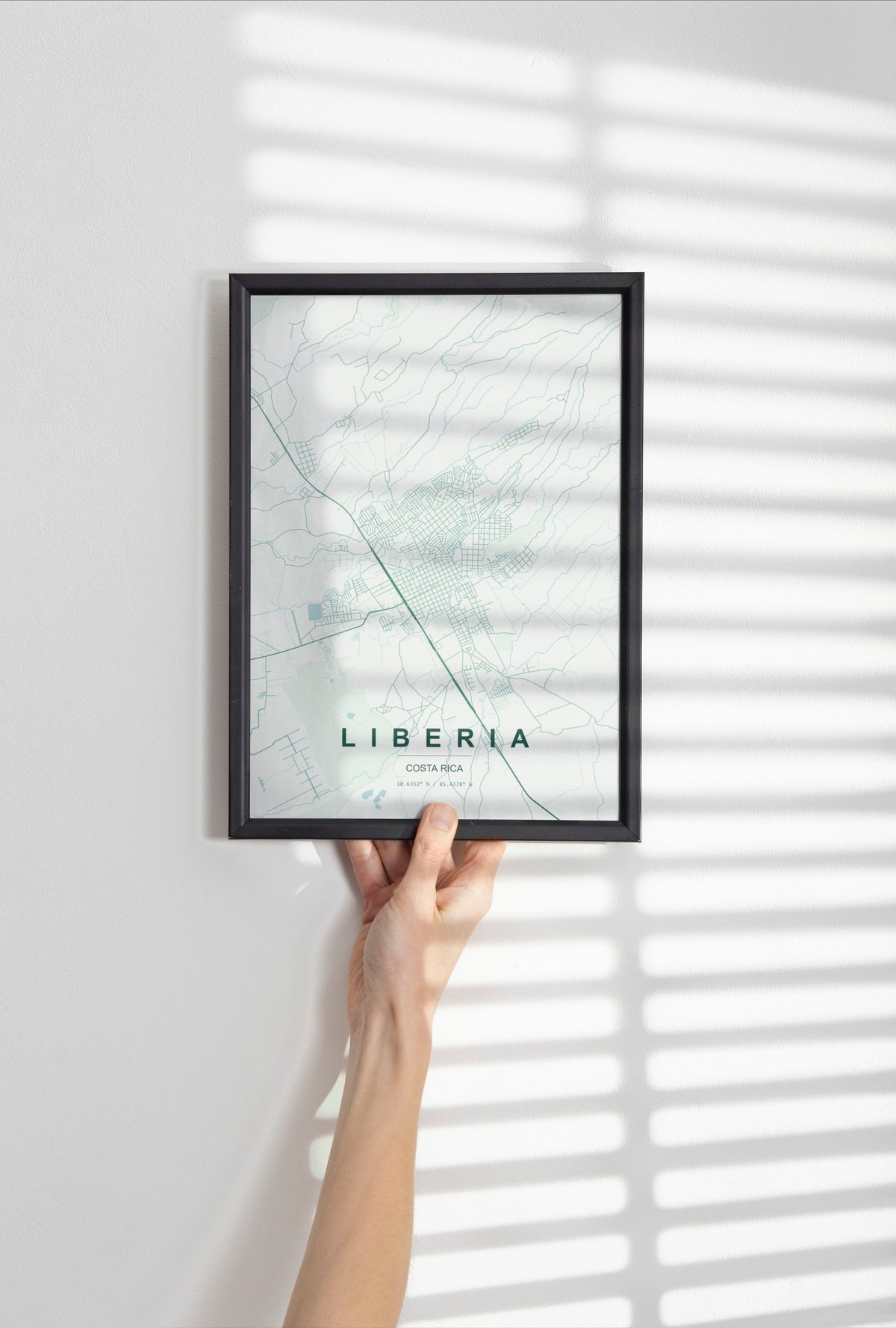 Liberia, Costa Rica map print in the Forest theme in a black frame held against a pale wall