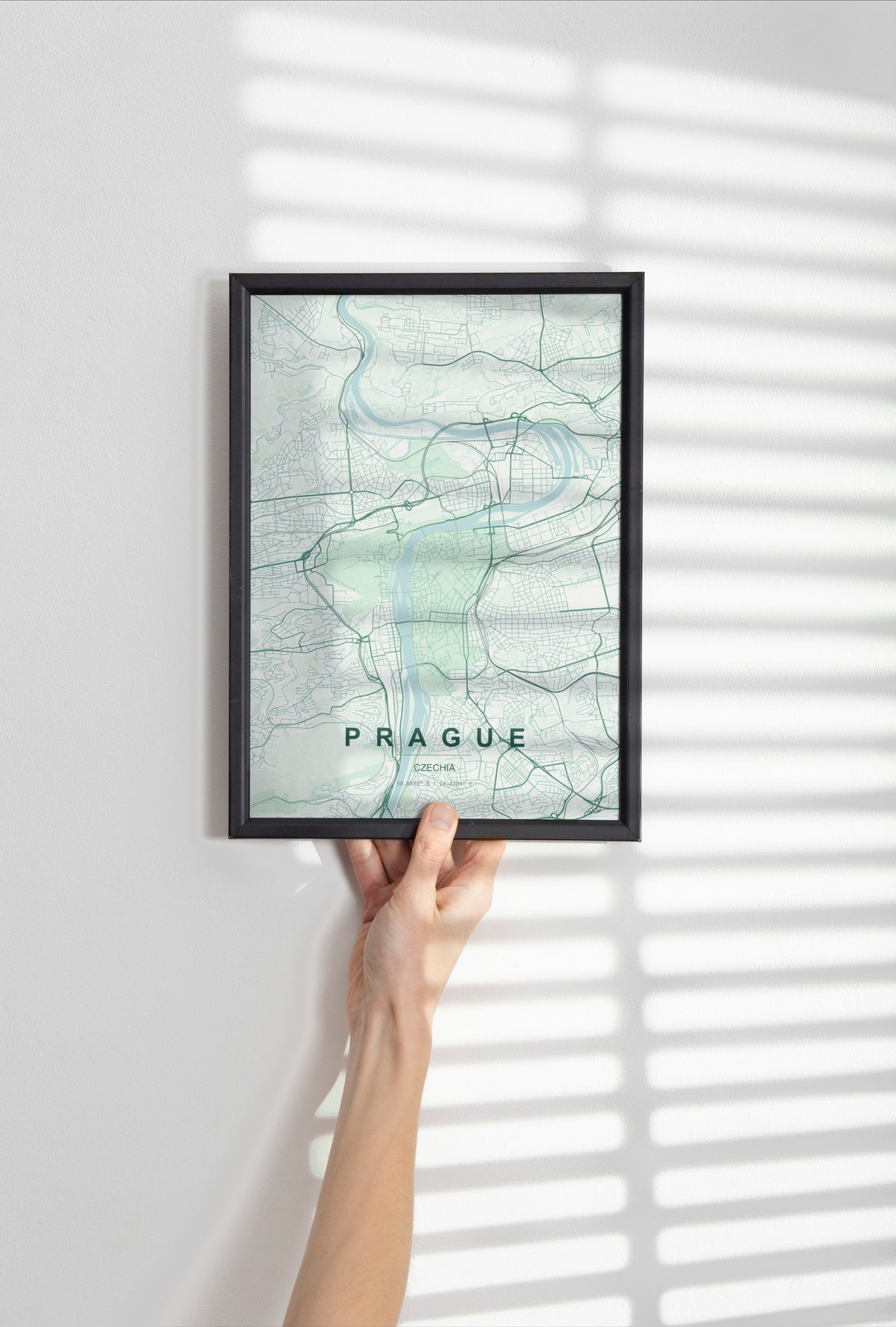Prague map print in the Forest theme in a black frame held against a pale wall