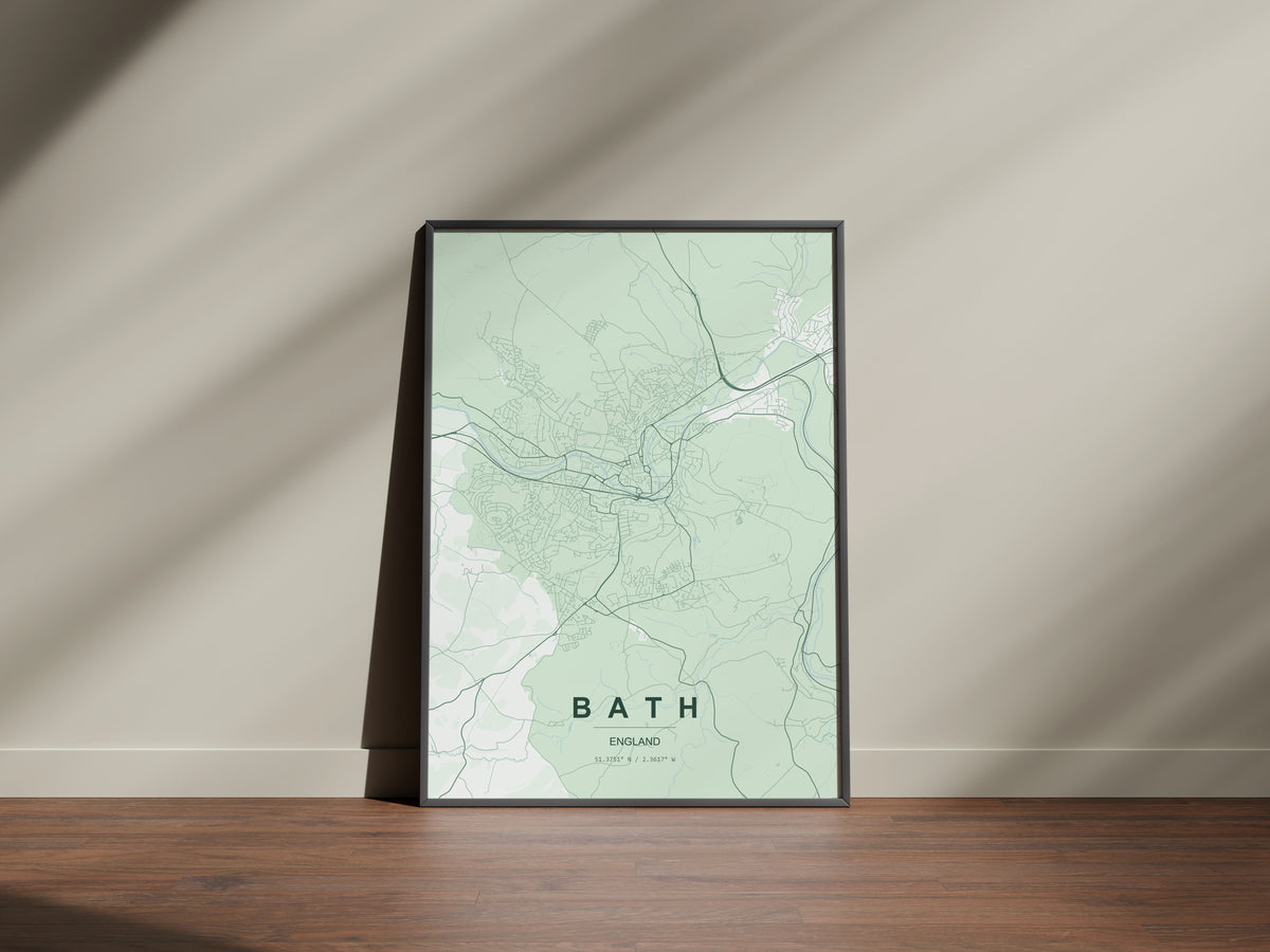 Example artwork, not your finished custom map: Bath map print in the Forest theme in a black frame on a wooden surface against a pale wall