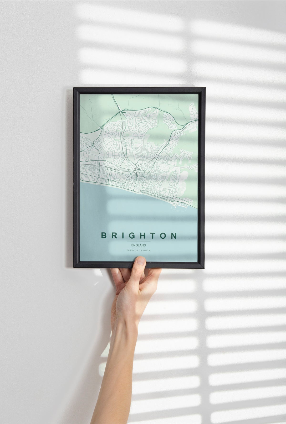 Brighton map print in the Forest theme in a black frame held against a pale wall