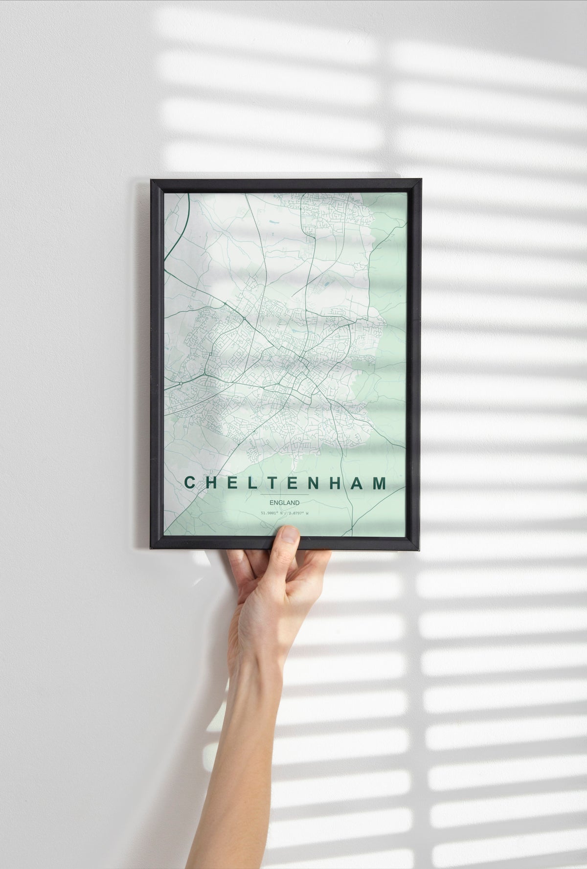 Cheltenham, England, United Kingdom map print in the Forest theme in a black frame held against a pale wall