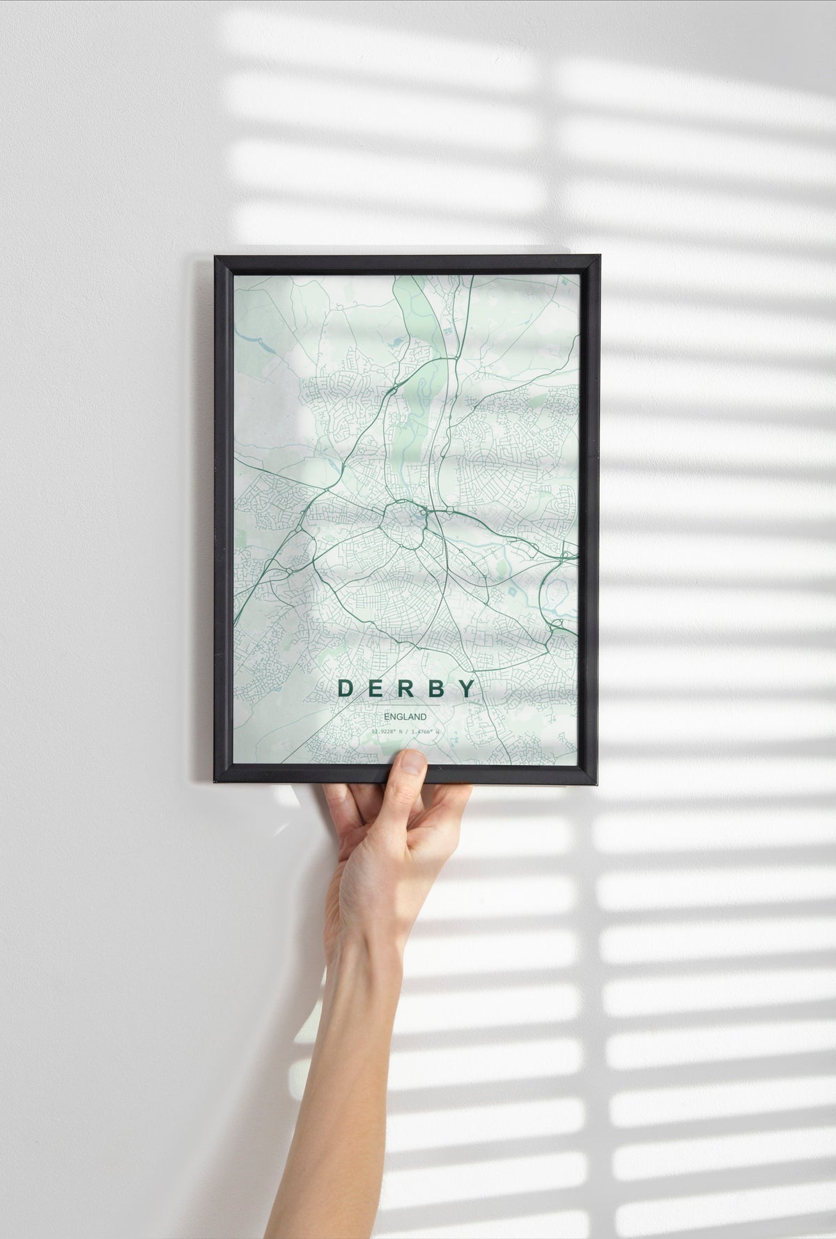 Derby, England, United Kingdom map print in the Forest theme in a black frame held against a pale wall