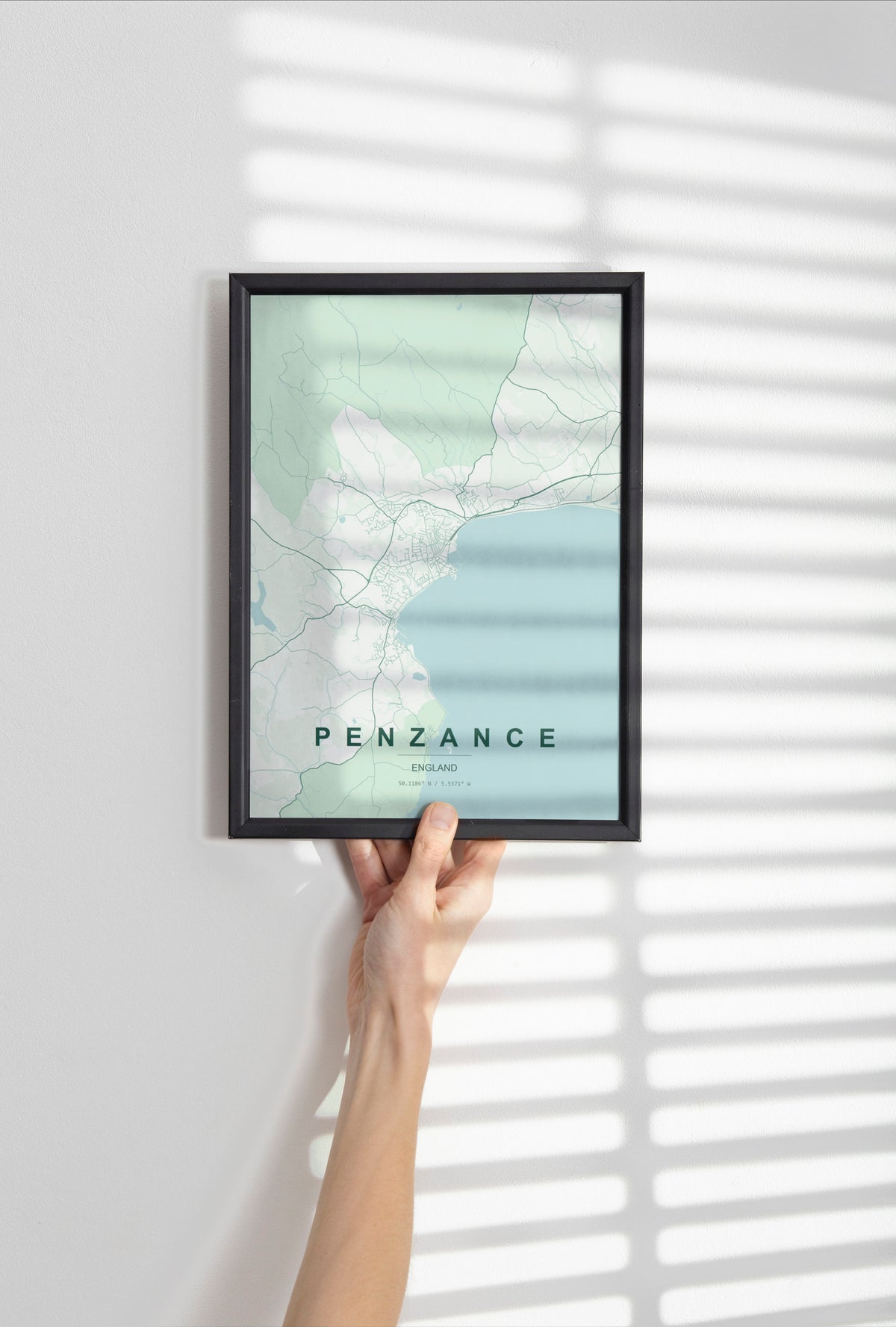 Penzance, England, United Kingdom map print in the Forest theme in a black frame held against a pale wall