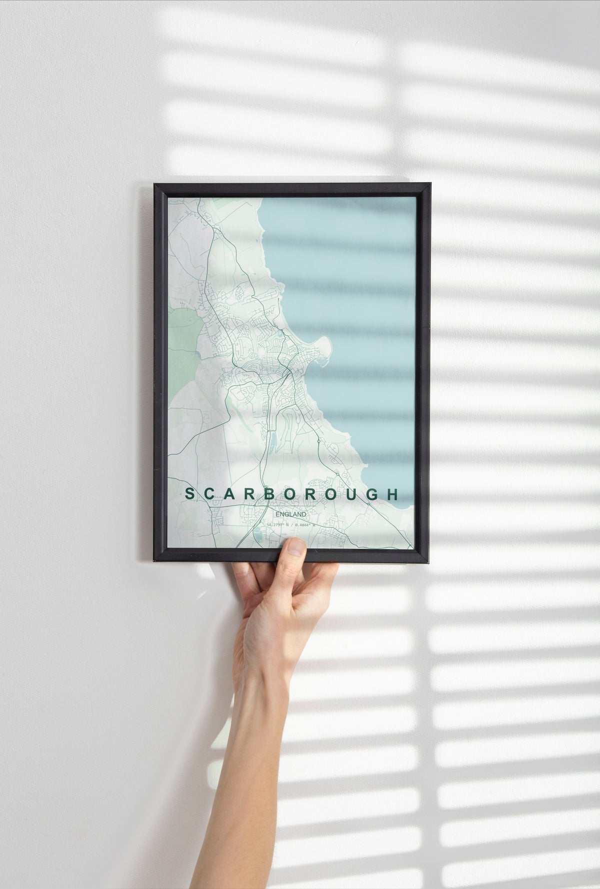 Scarborough, England, United Kingdom map print in the Forest theme in a black frame held against a pale wall