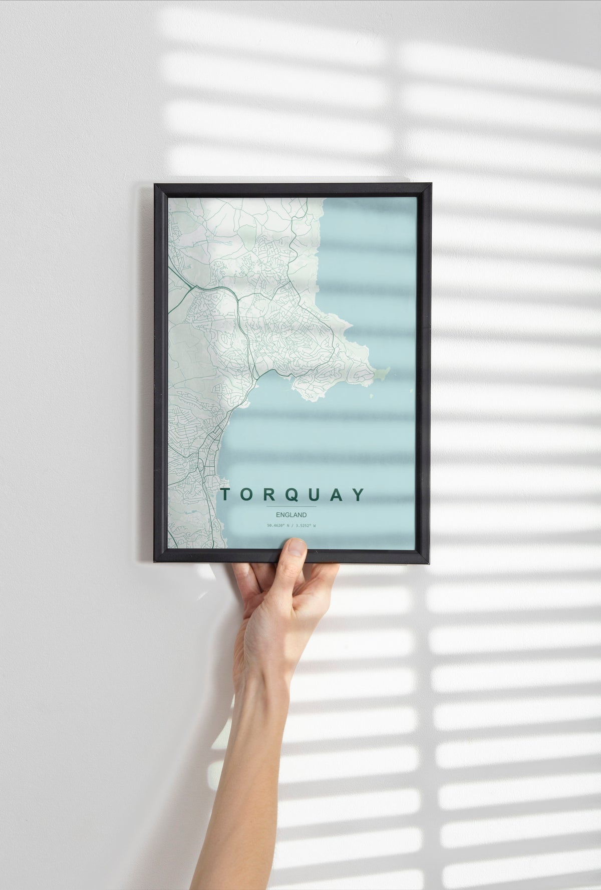 Torquay, England, United Kingdom map print in the Forest theme in a black frame held against a pale wall
