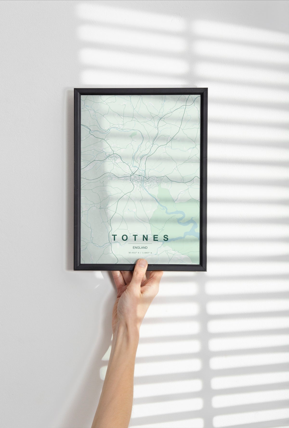Totnes, England, United Kingdom map print in the Forest theme in a black frame held against a pale wall
