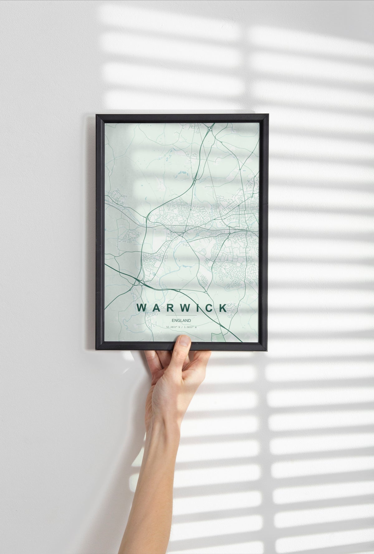 Warwick, England, United Kingdom map print in the Forest theme in a black frame held against a pale wall