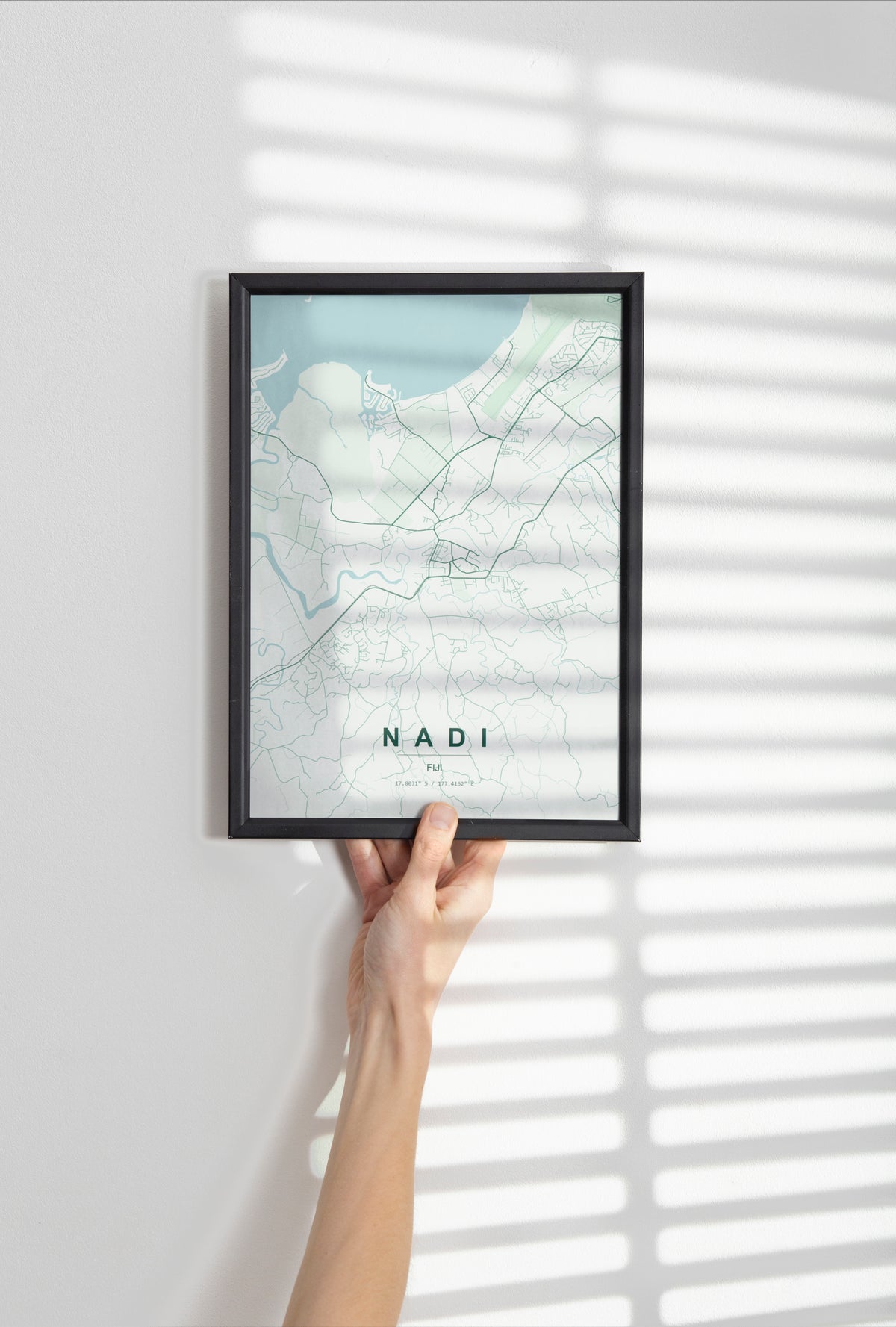 Nadi, Fiji map print in the Forest theme in a black frame held against a pale wall