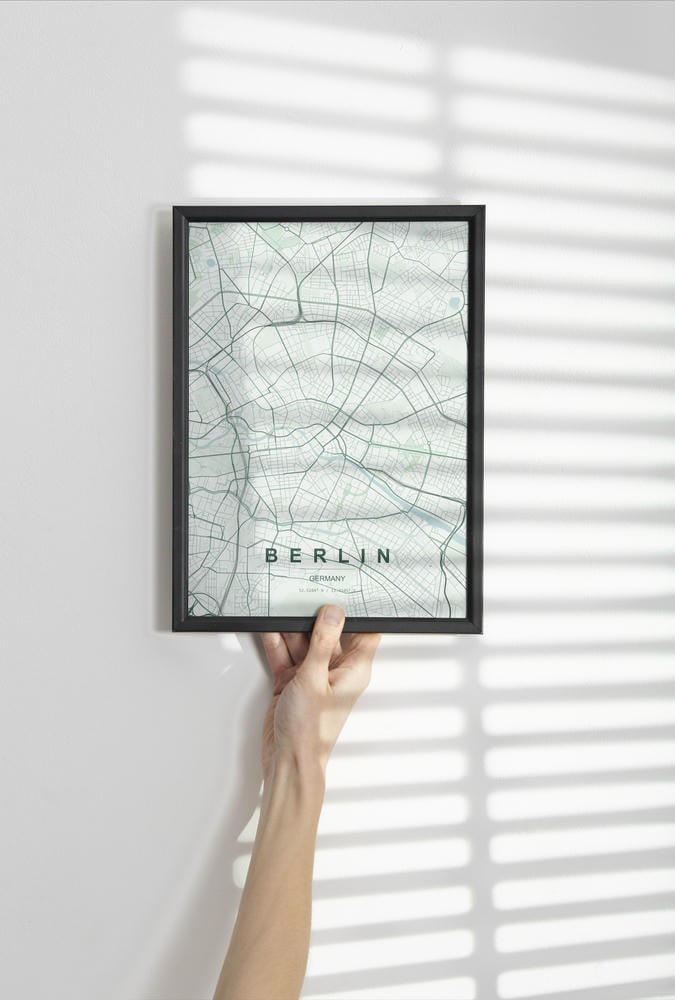 Berlin map print in the Forest theme in a black frame held against a pale wall