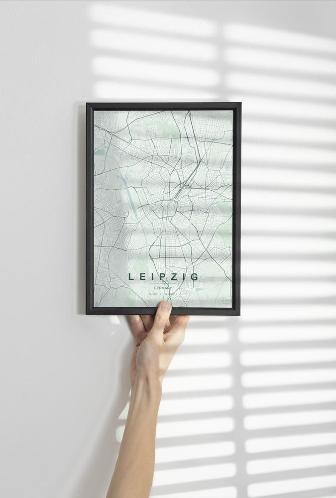 Leipzig map print in the Forest theme in a black frame held against a pale wall