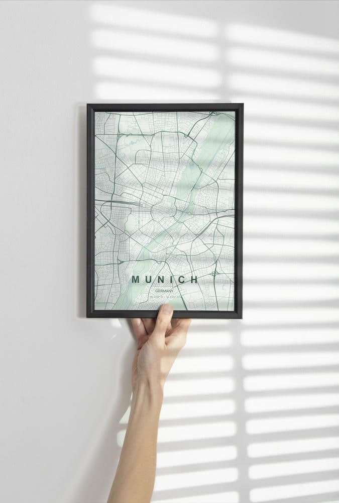 Munich map print in the Forest theme in a black frame held against a pale wall