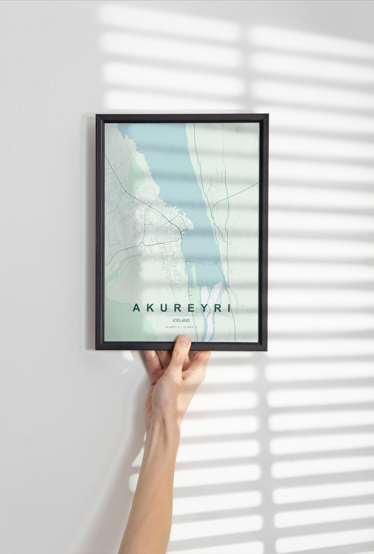 Akureyri map print in the Forest theme in a black frame held against a pale wall