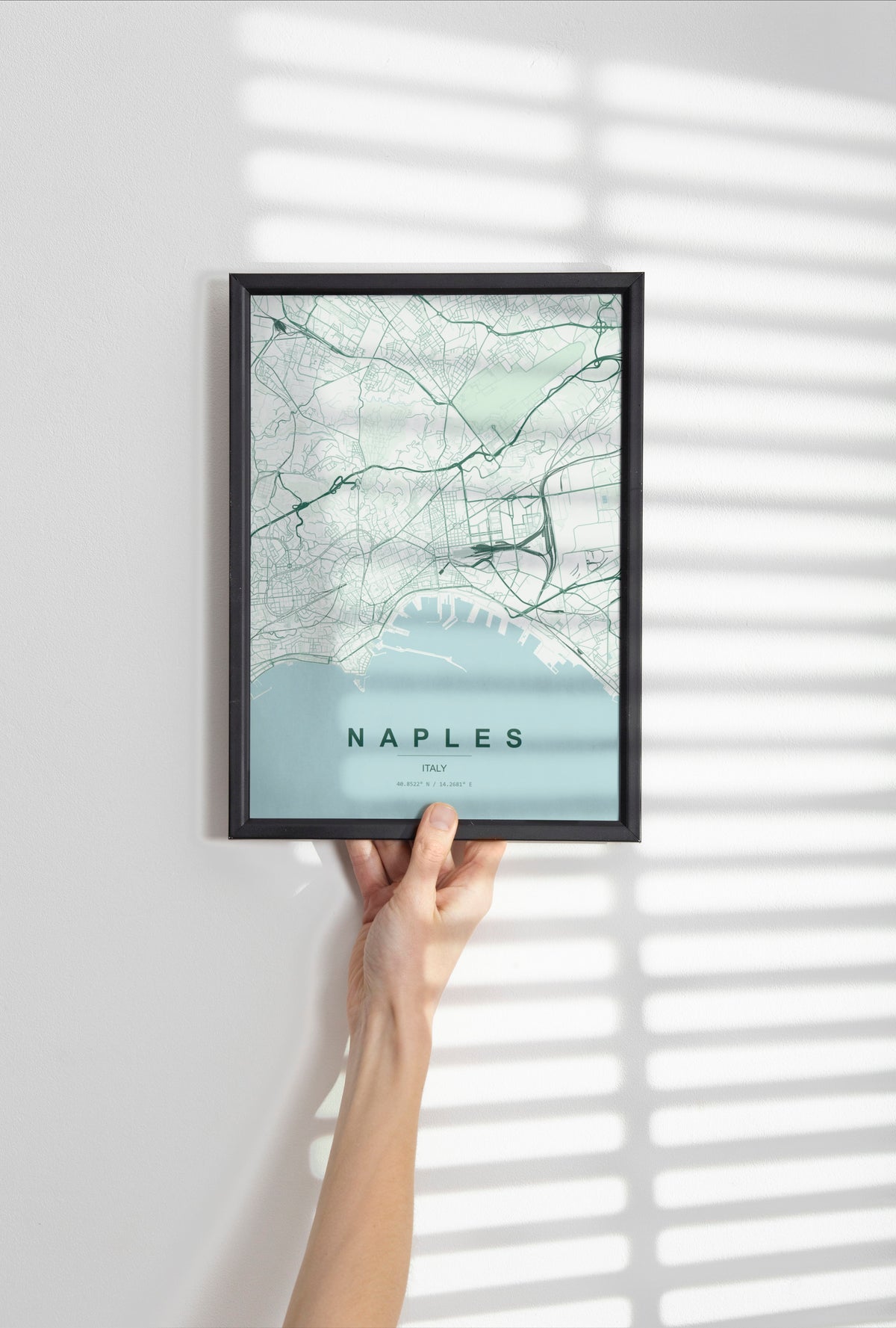 Naples map print in the Forest theme in a black frame held against a pale wall