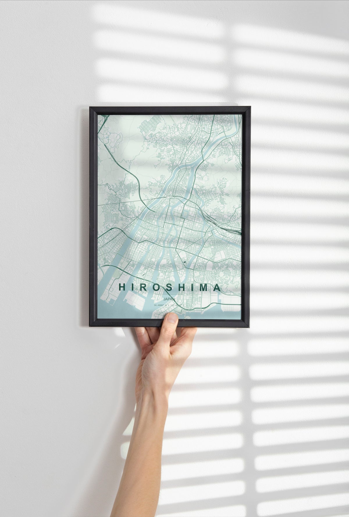 Hiroshima, Japan map print in the Forest theme in a black frame held against a pale wall