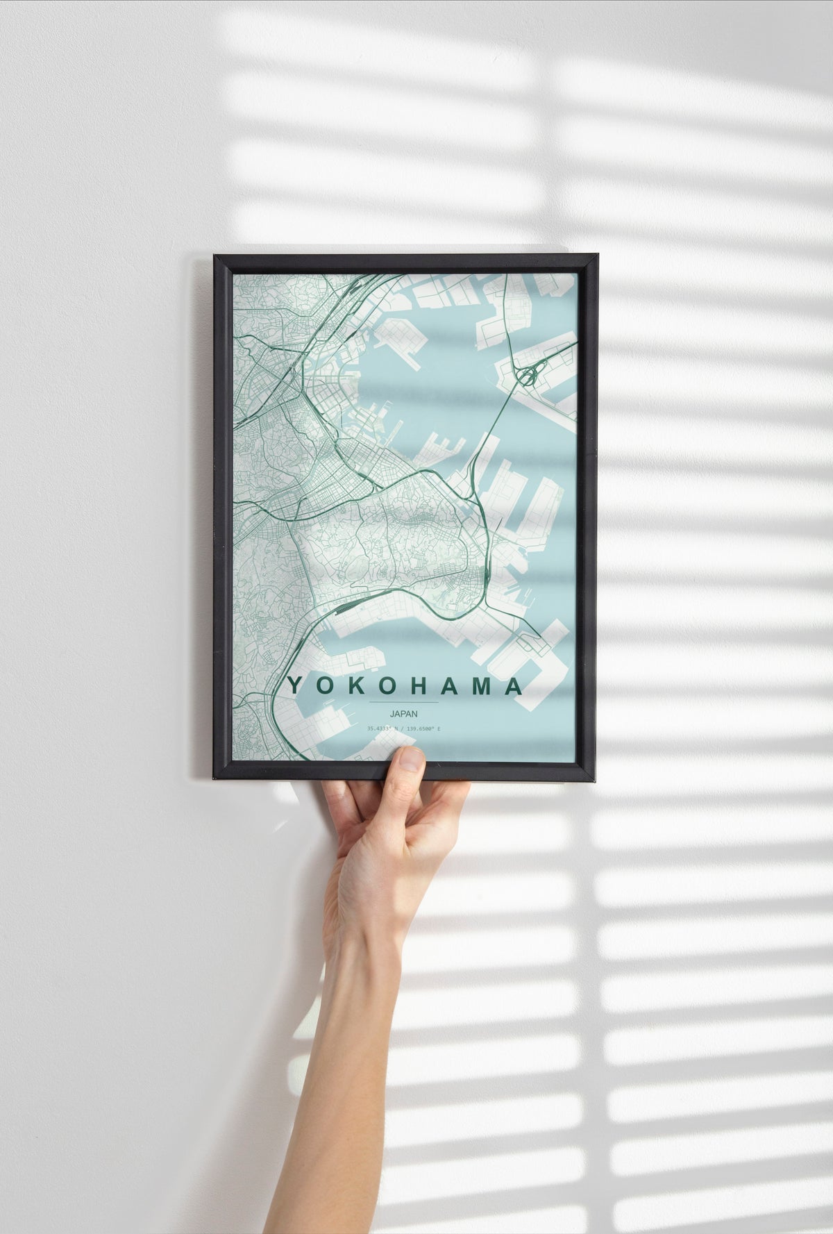 Yokohama, Japan map print in the Forest theme in a black frame held against a pale wall