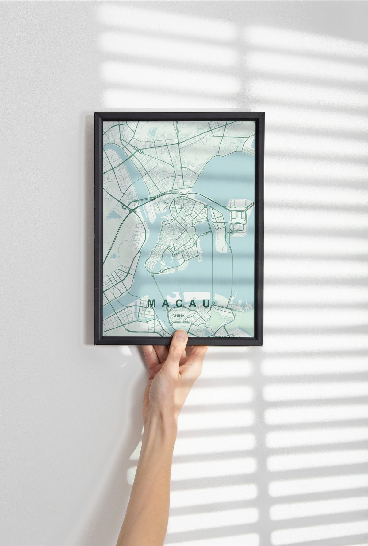 Macau, China map print in the Forest theme in a black frame held against a pale wall