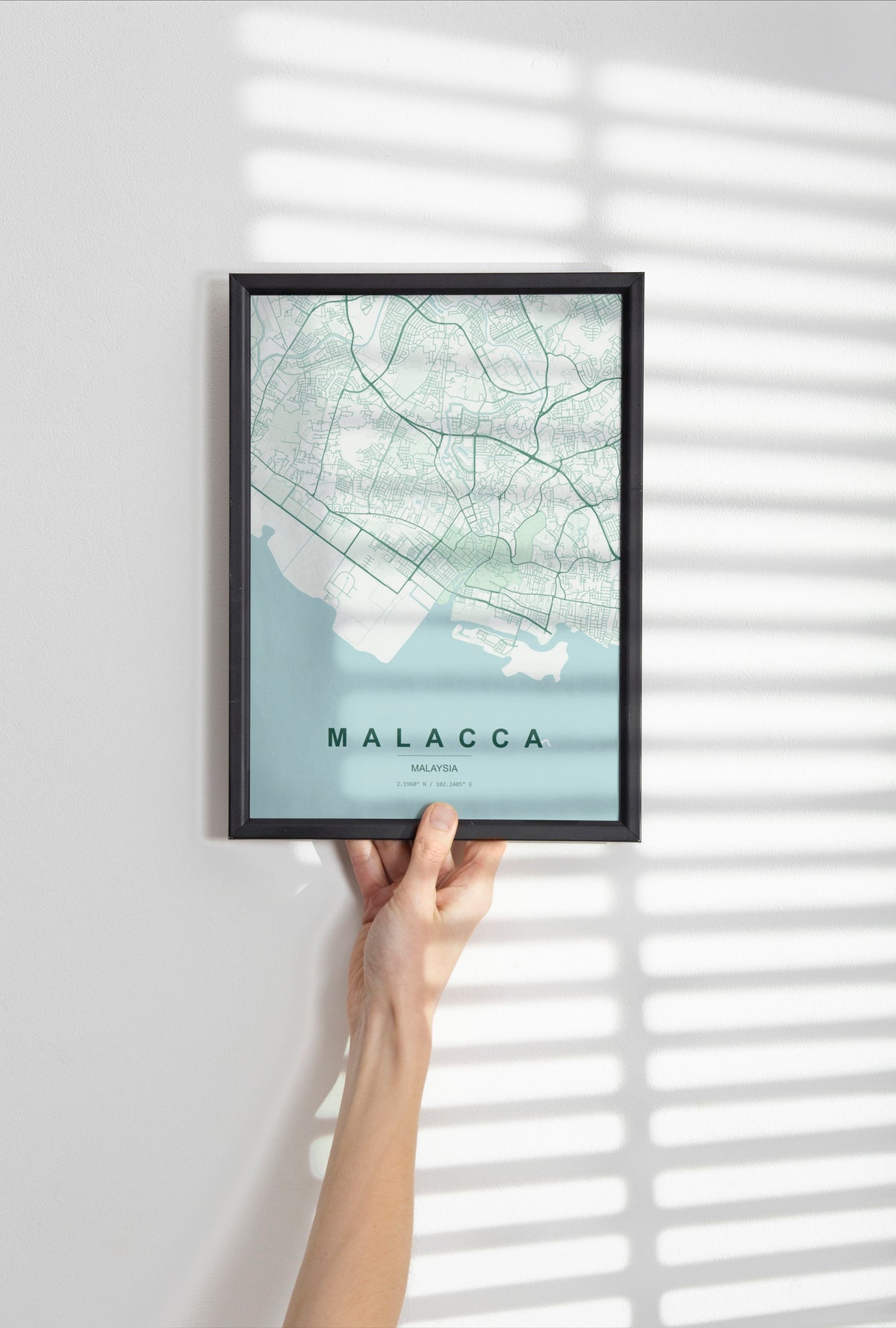 Malacca, Malaysia map print in the Forest theme in a black frame held against a pale wall