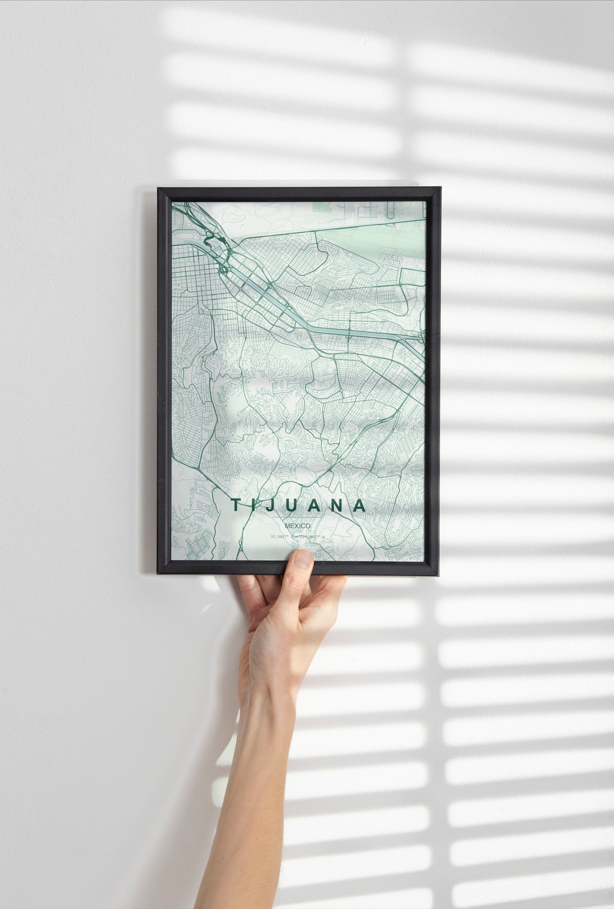 Tijuana, Mexico map print in the Forest theme in a black frame held against a pale wall