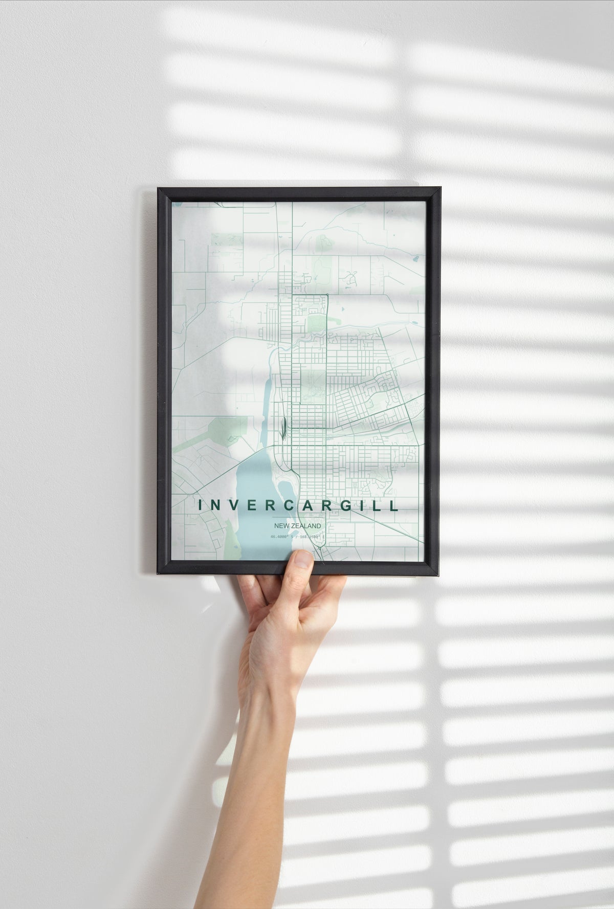 Invercargill, Southland, New Zealand map print in the Forest theme in a black frame held against a pale wall