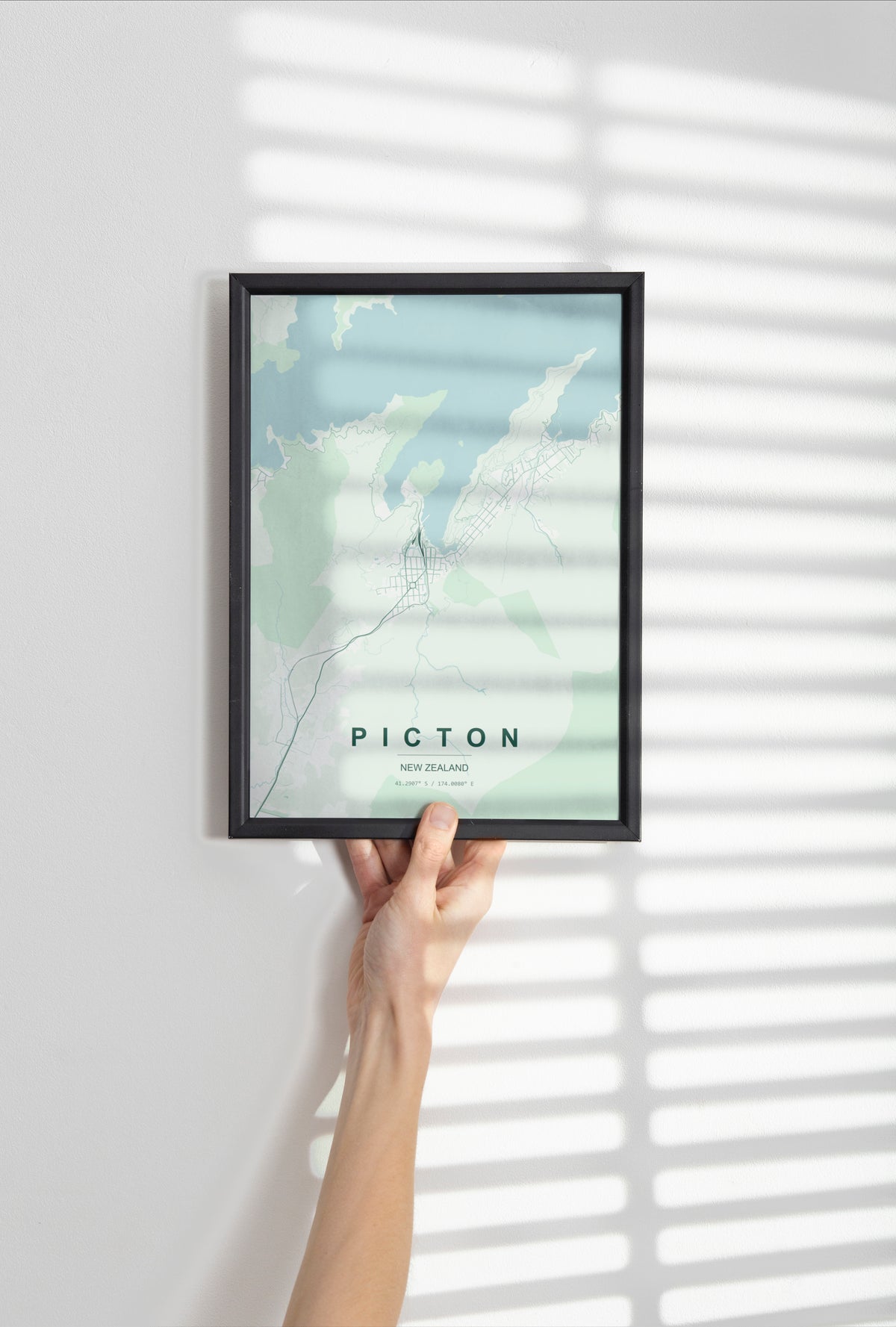 Picton, Marlborough, New Zealand map print in the Forest theme in a black frame held against a pale wall