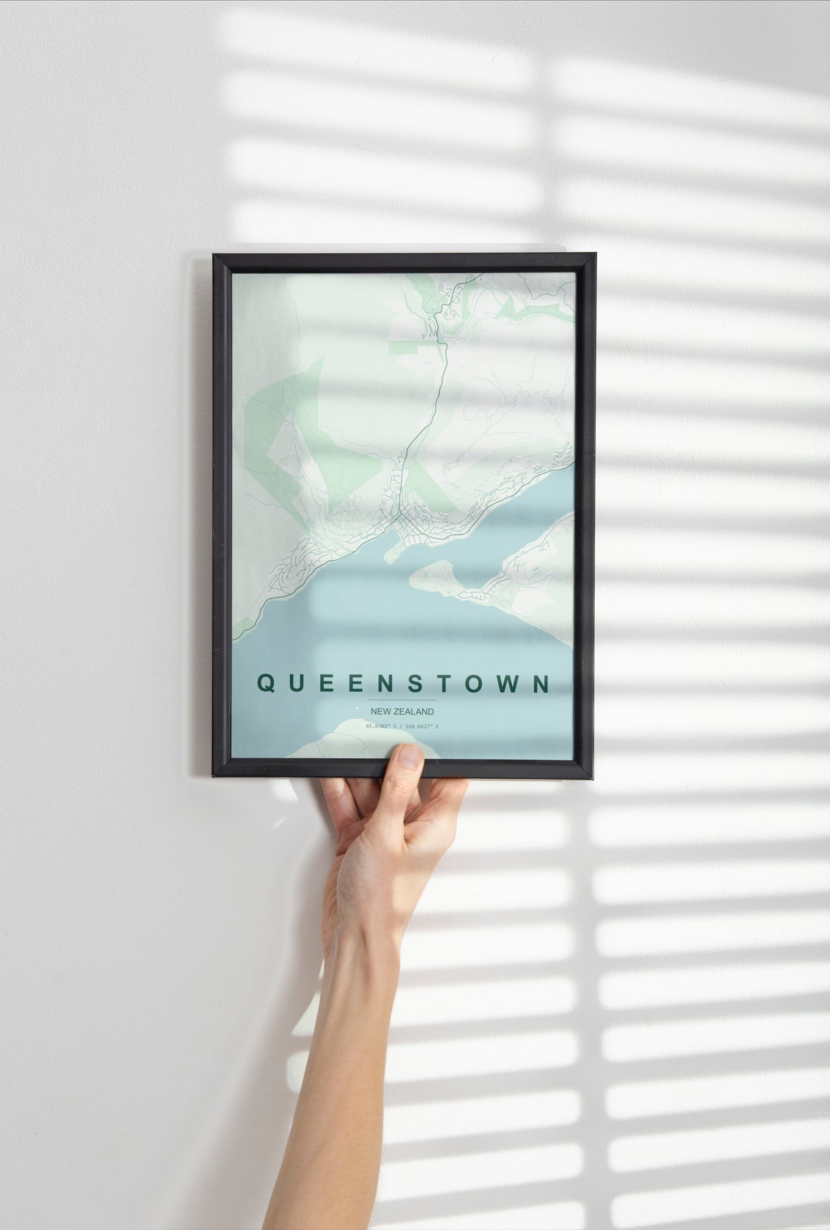 Queenstown, Otago, New Zealand map print in the Forest theme in a black frame held against a pale wall