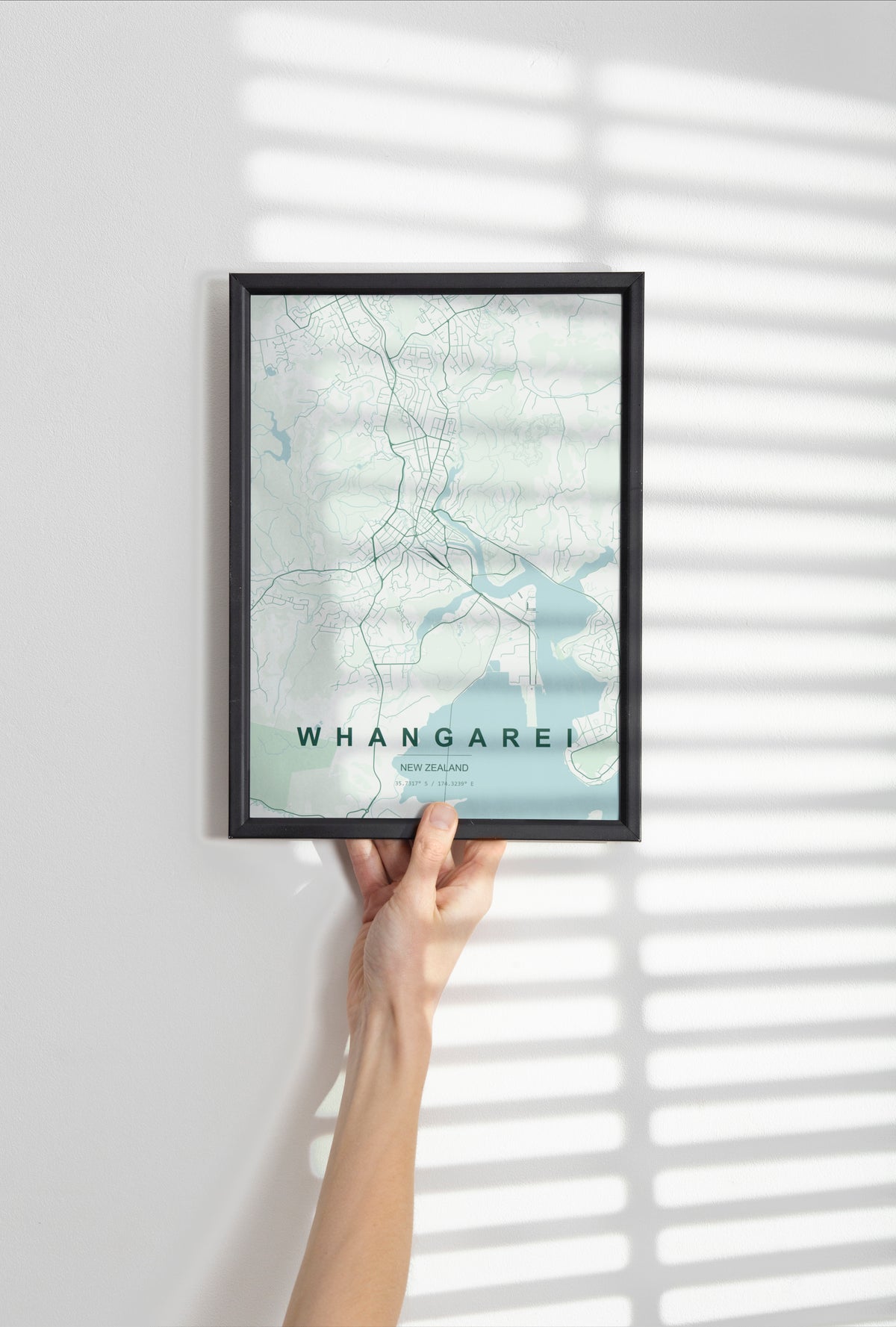 Whangārei, Northland, New Zealand map print in the Forest theme in a black frame held against a pale wall