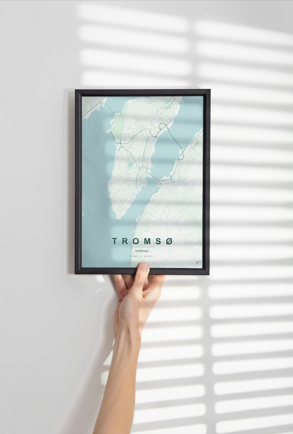 Tromsø map print in the Forest theme in a black frame held against a pale wall