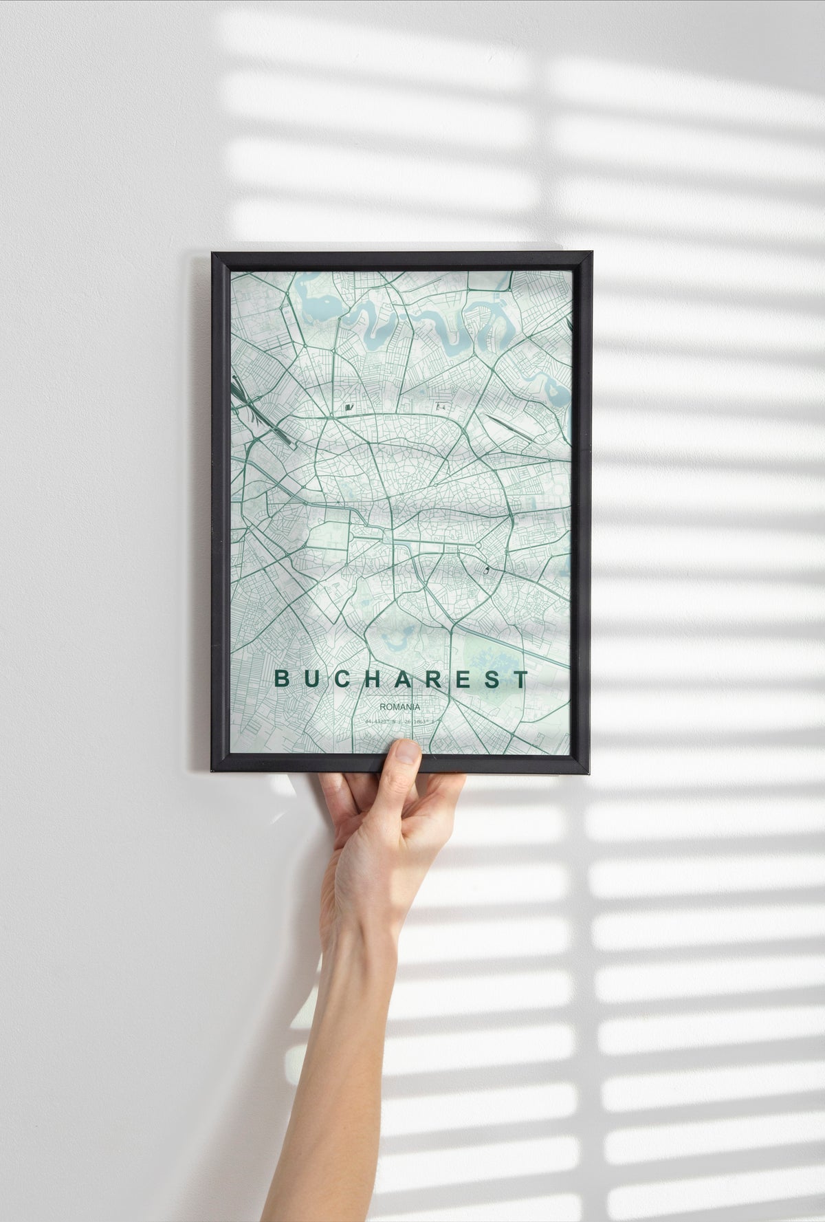Bucharest map print in the Forest theme in a black frame held against a pale wall