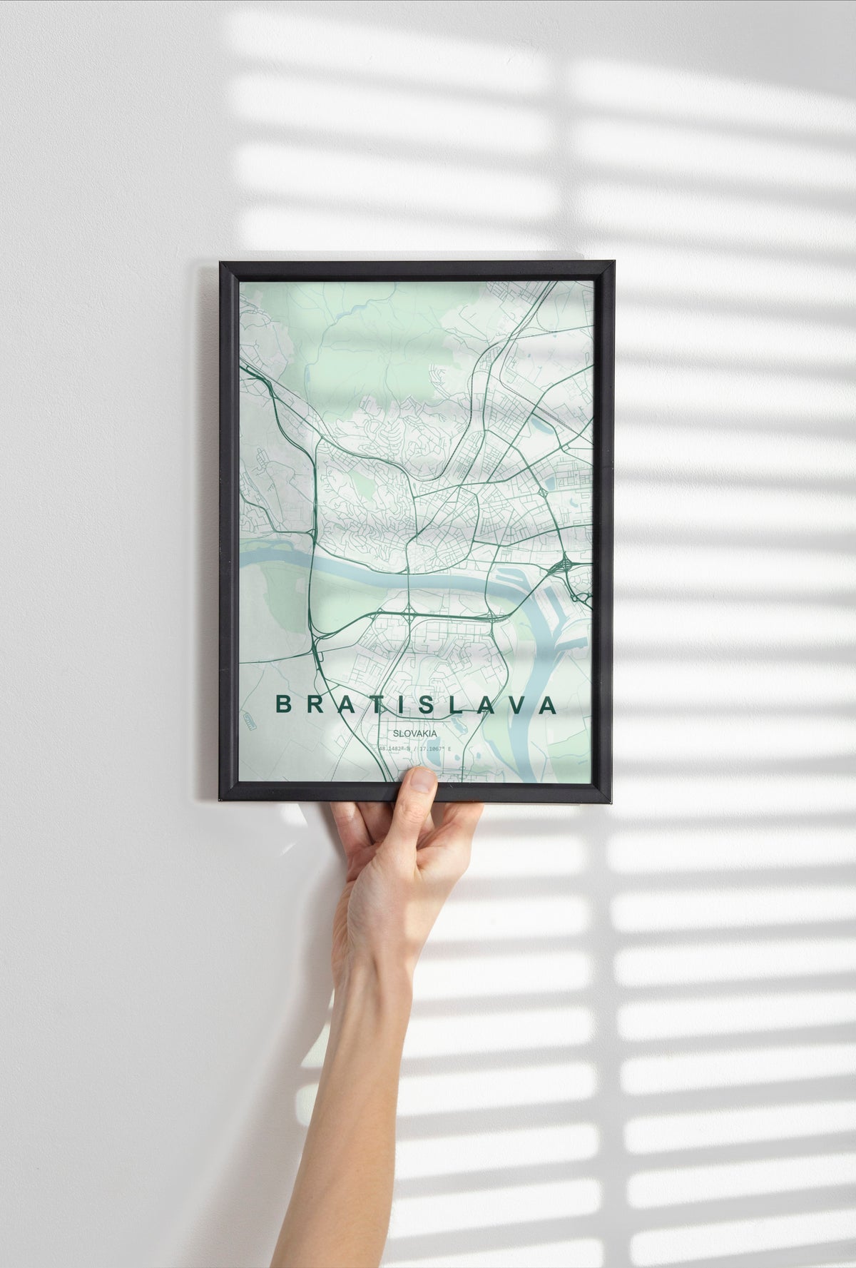 Bratislava map print in the Forest theme in a black frame held against a pale wall