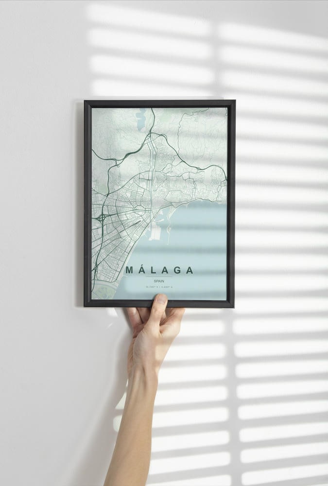 Málaga map print in the Forest theme in a black frame held against a pale wall
