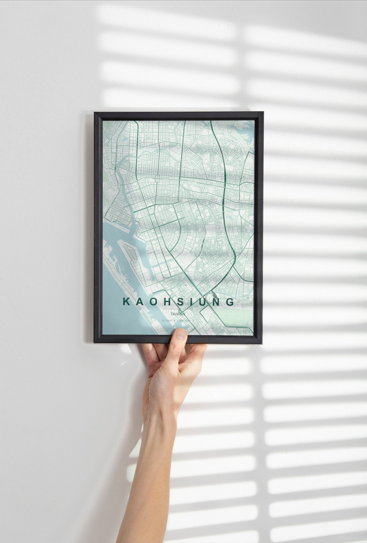 Kaohsiung, Taiwan map print in the Forest theme in a black frame held against a pale wall