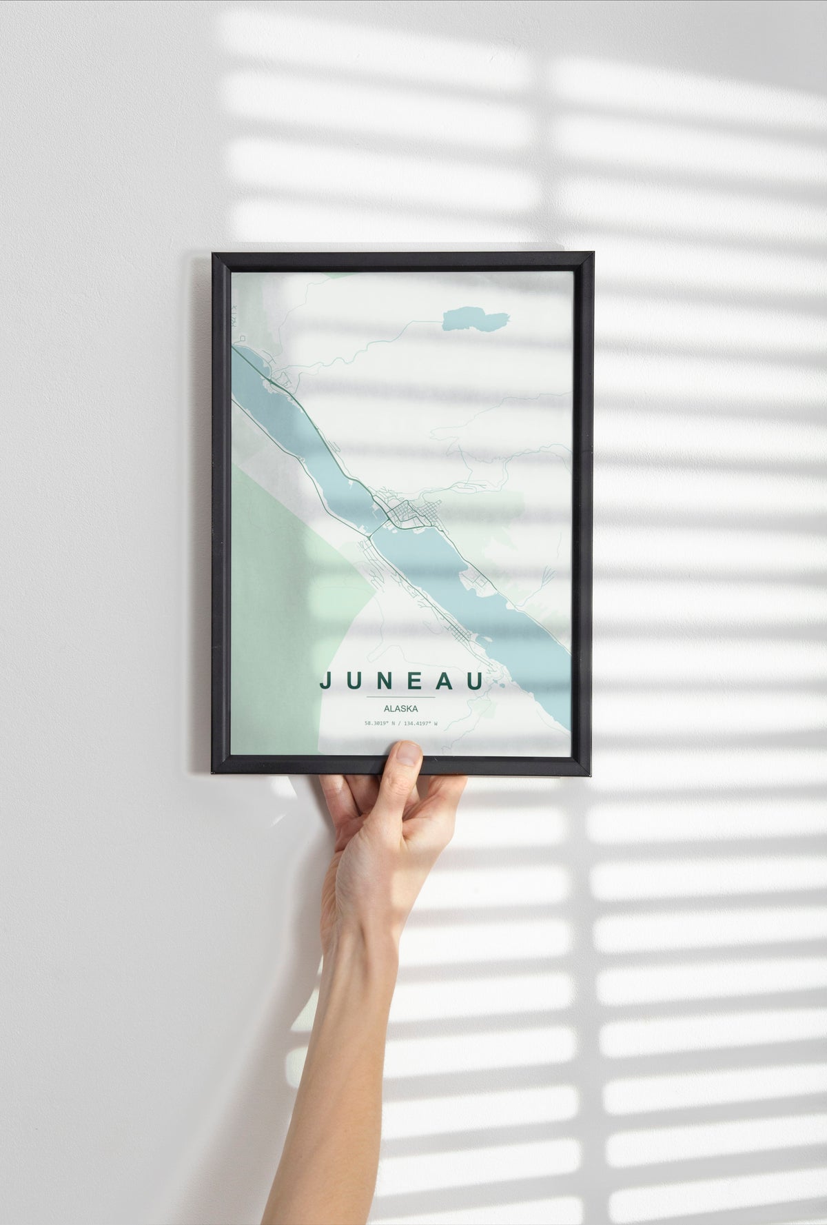 Juneau, Alaska, United States map print in the Forest theme in a black frame held against a pale wall