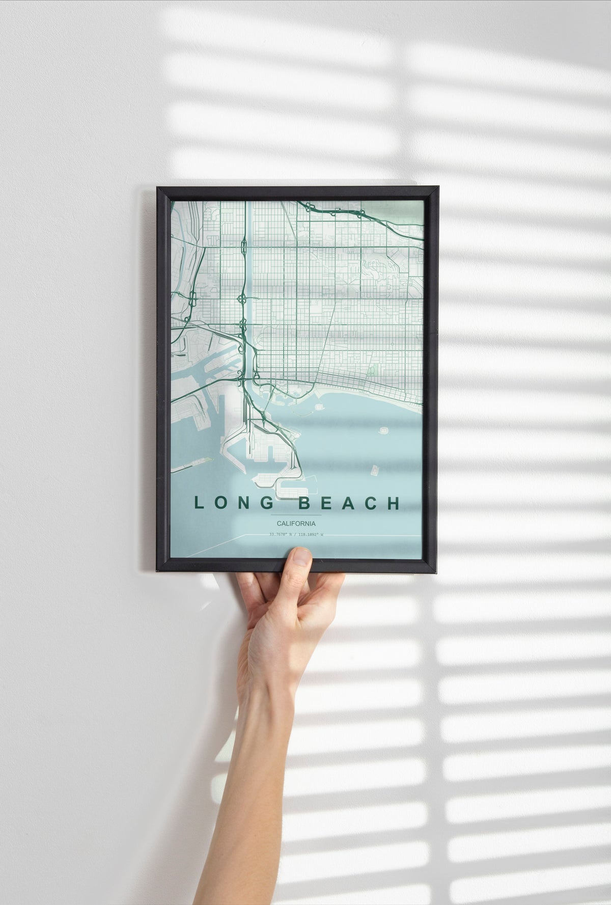 Long Beach map print in the Forest theme in a black frame held against a pale wall
