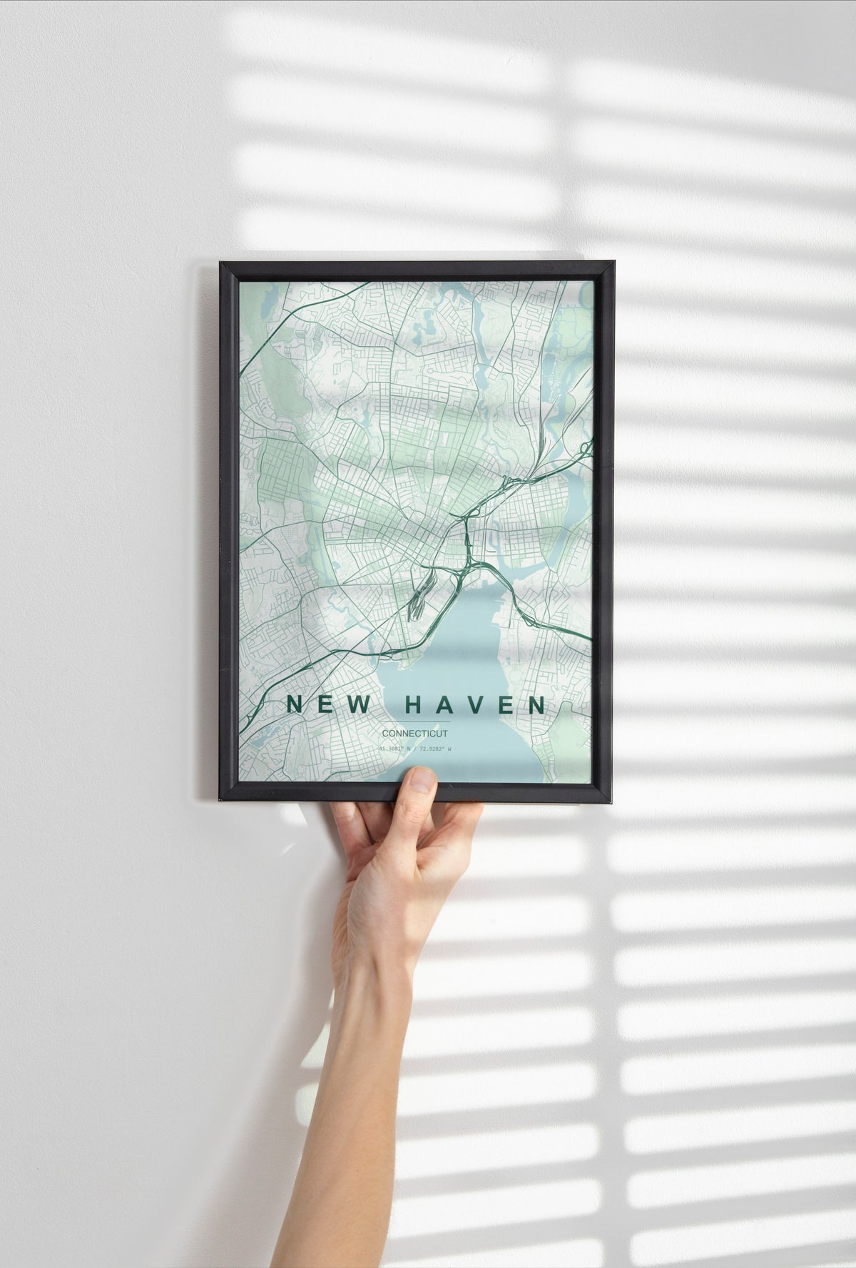 New Haven map print in the Forest theme in a black frame held against a pale wall