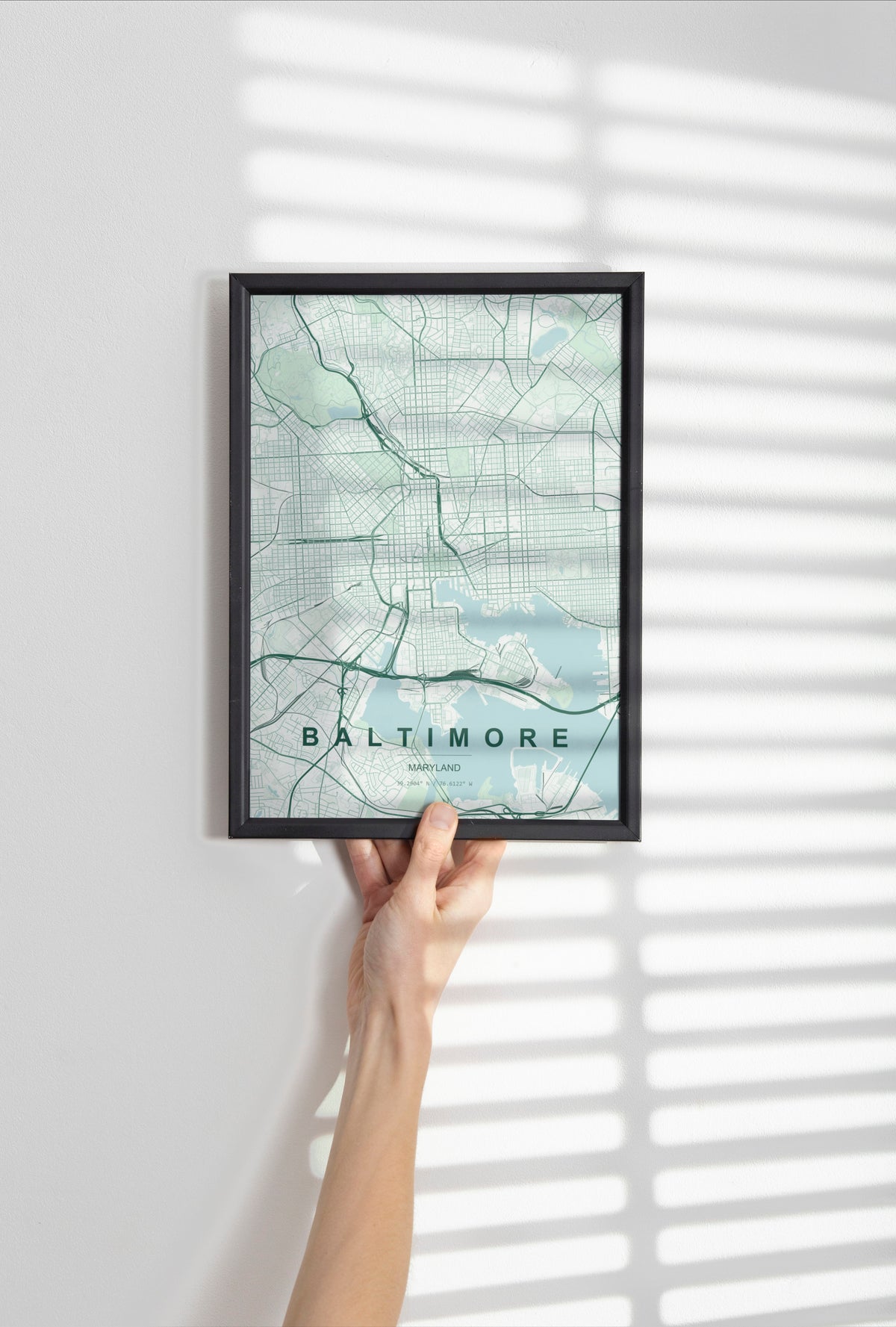 Baltimore map print in the Forest theme in a black frame held against a pale wall