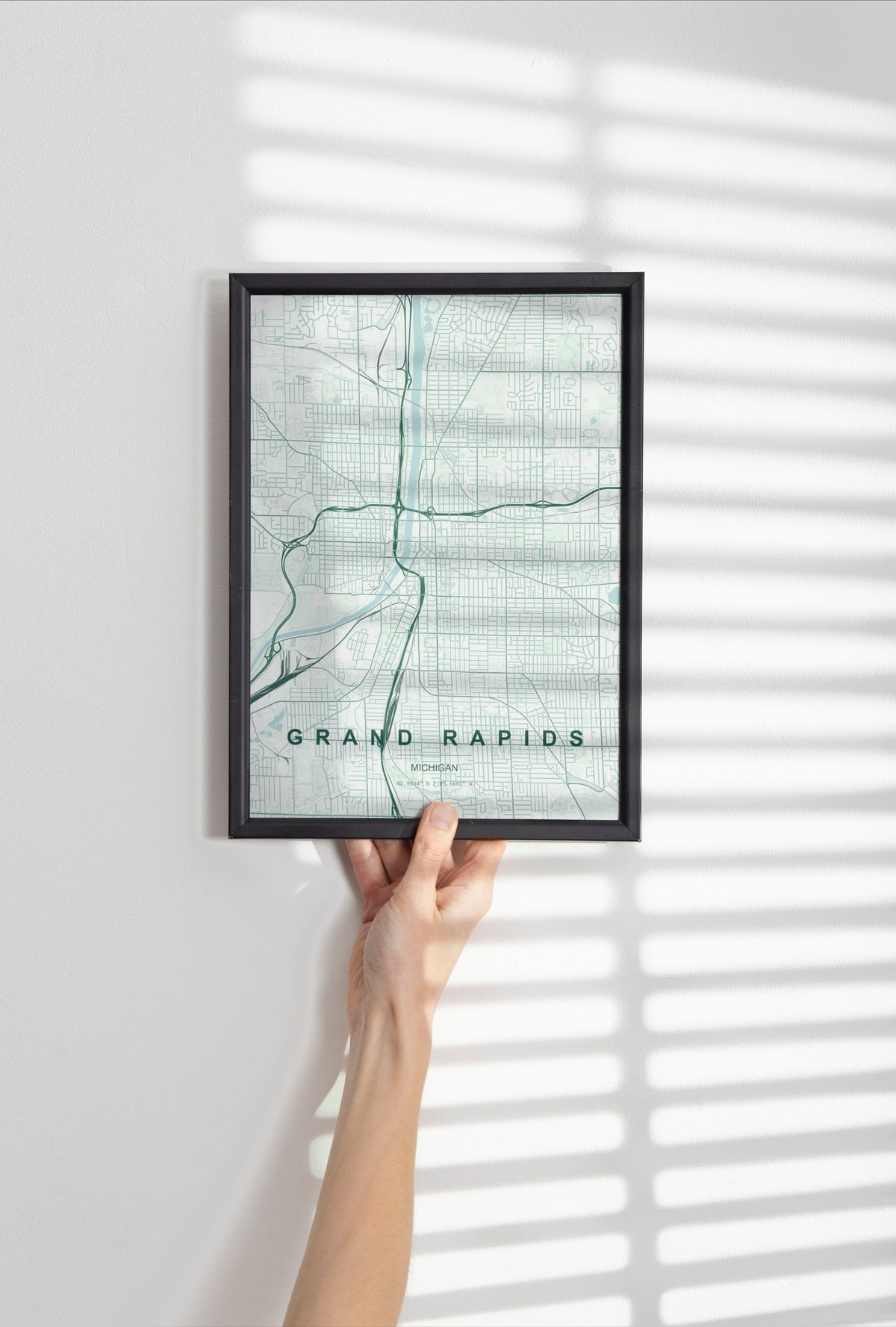 Grand Rapids map print in the Forest theme in a black frame held against a pale wall