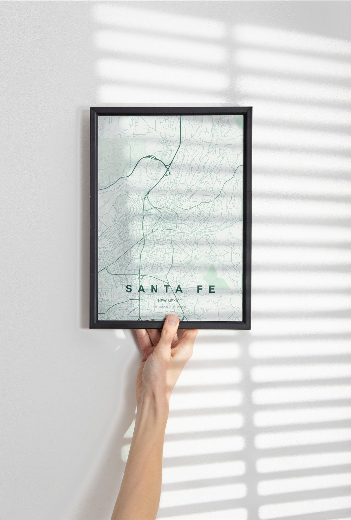 Santa Fe map print in the Forest theme in a black frame held against a pale wall