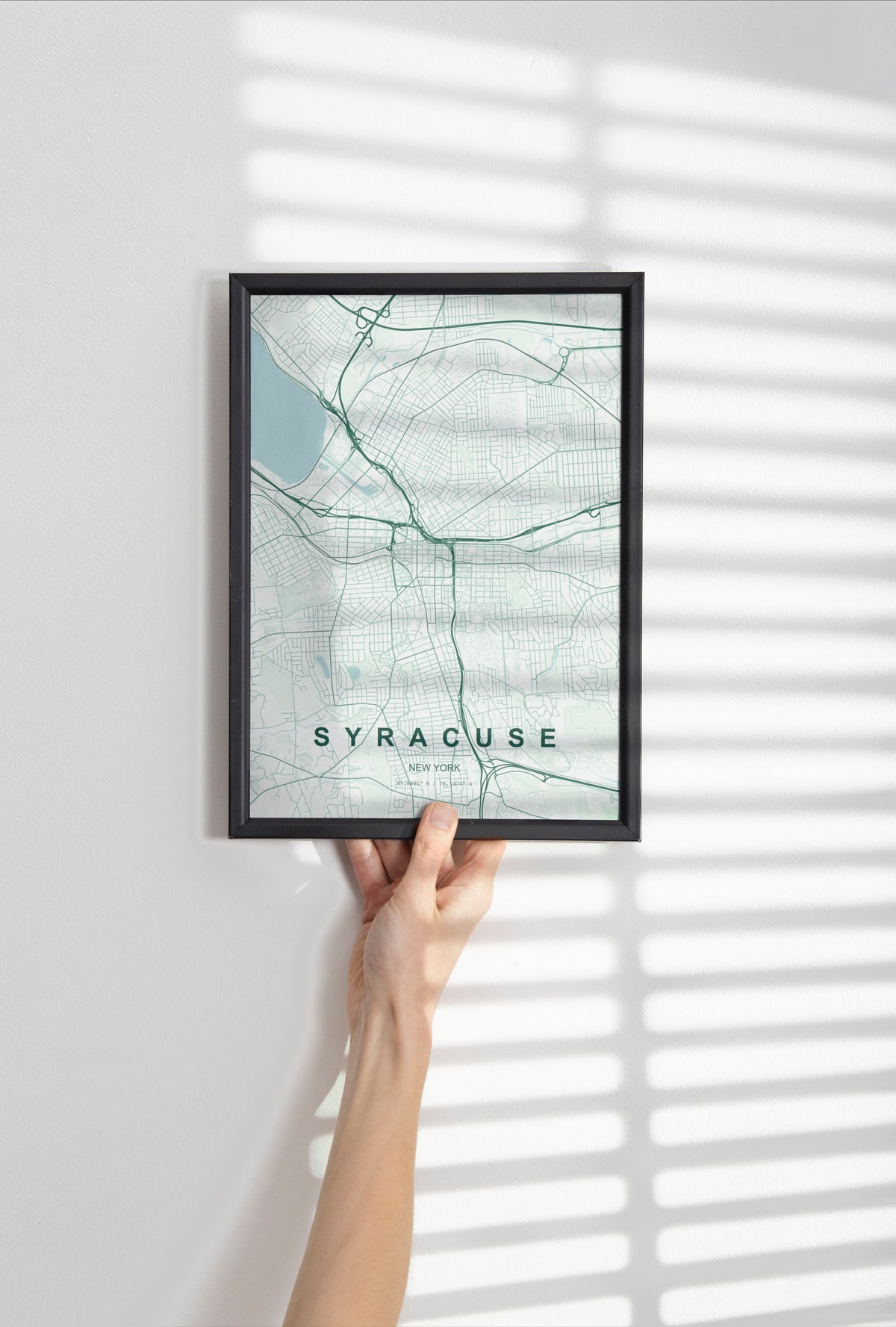 Syracuse map print in the Forest theme in a black frame held against a pale wall