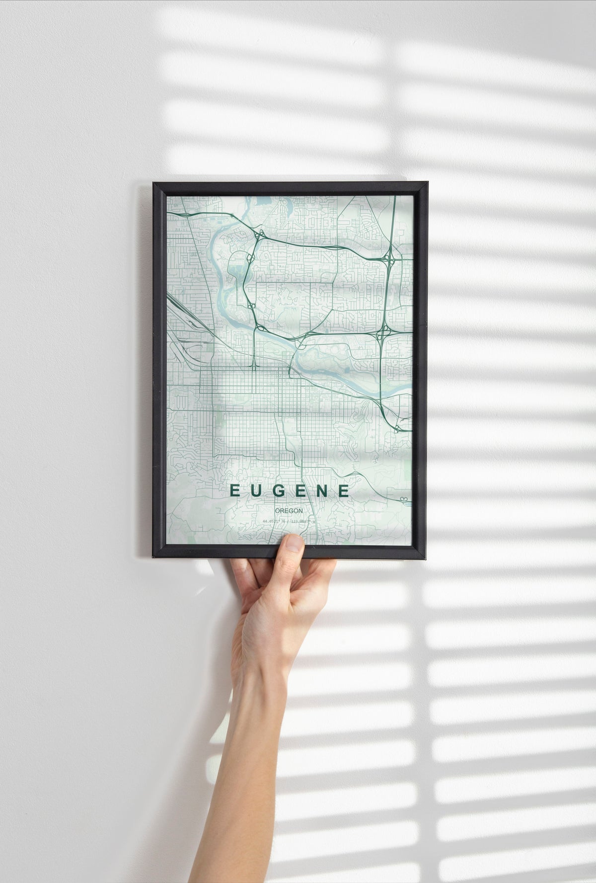 Eugene map print in the Forest theme in a black frame held against a pale wall