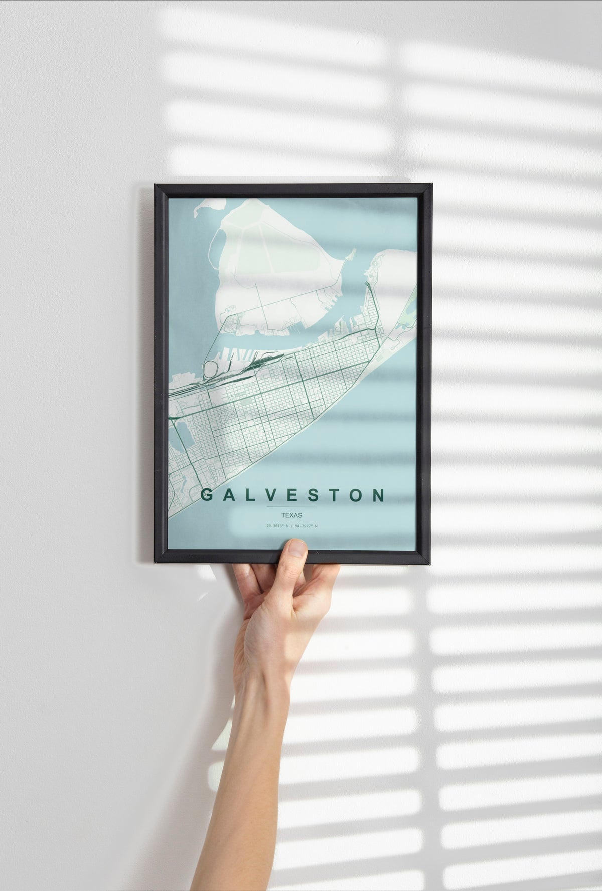 Galveston map print in the Forest theme in a black frame held against a pale wall