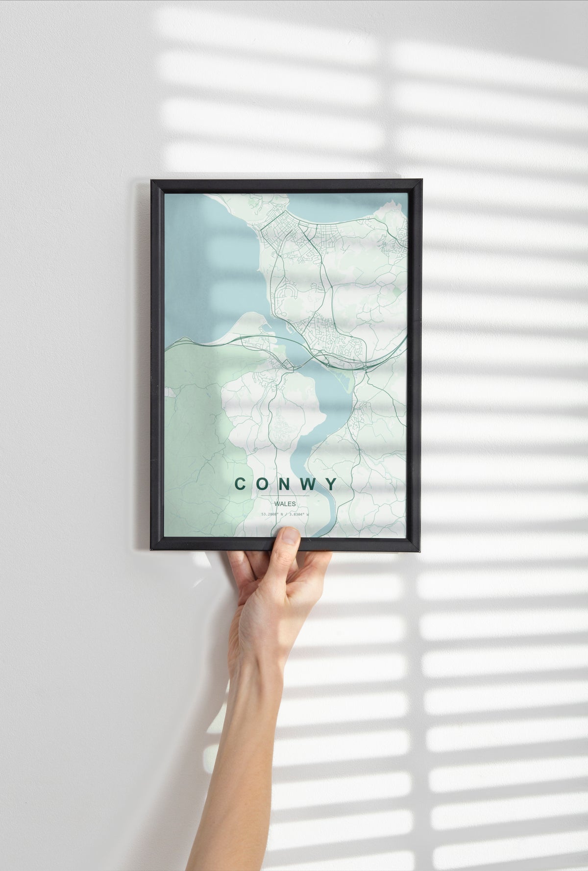 Conwy, Wales, United Kingdom map print in the Forest theme in a black frame held against a pale wall