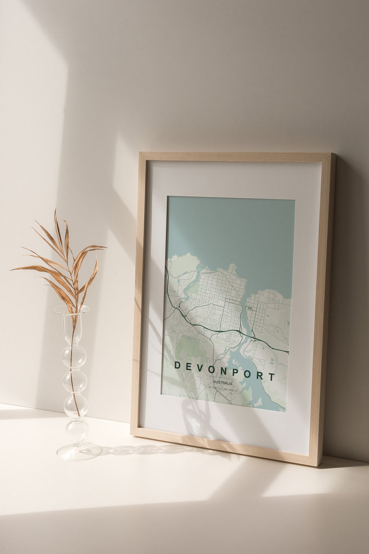 Devonport, Tasmania, Australia map print in the Forest theme in a light wooden frame on a shelf beside a glass vase